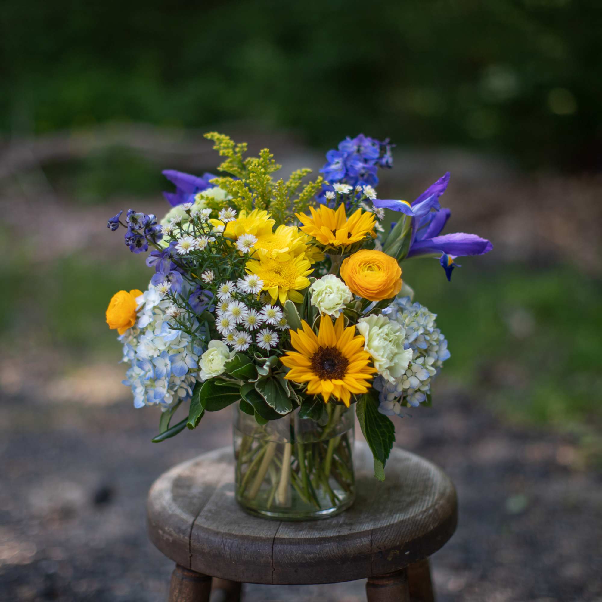Mixed bouquet of yellow, blue, and white flowers in a glass vase