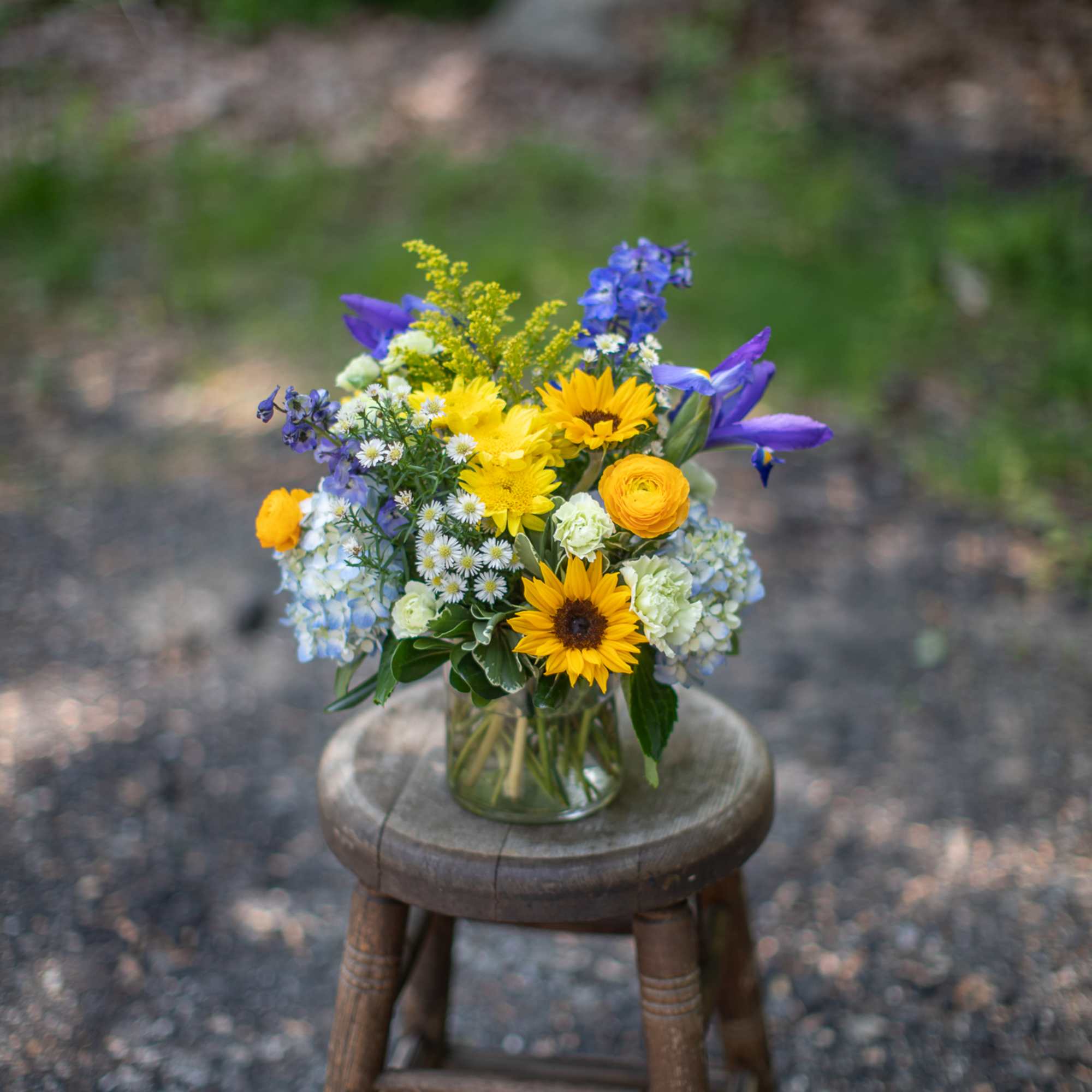 Mixed bouquet in a clear glass vase on a wooden stool