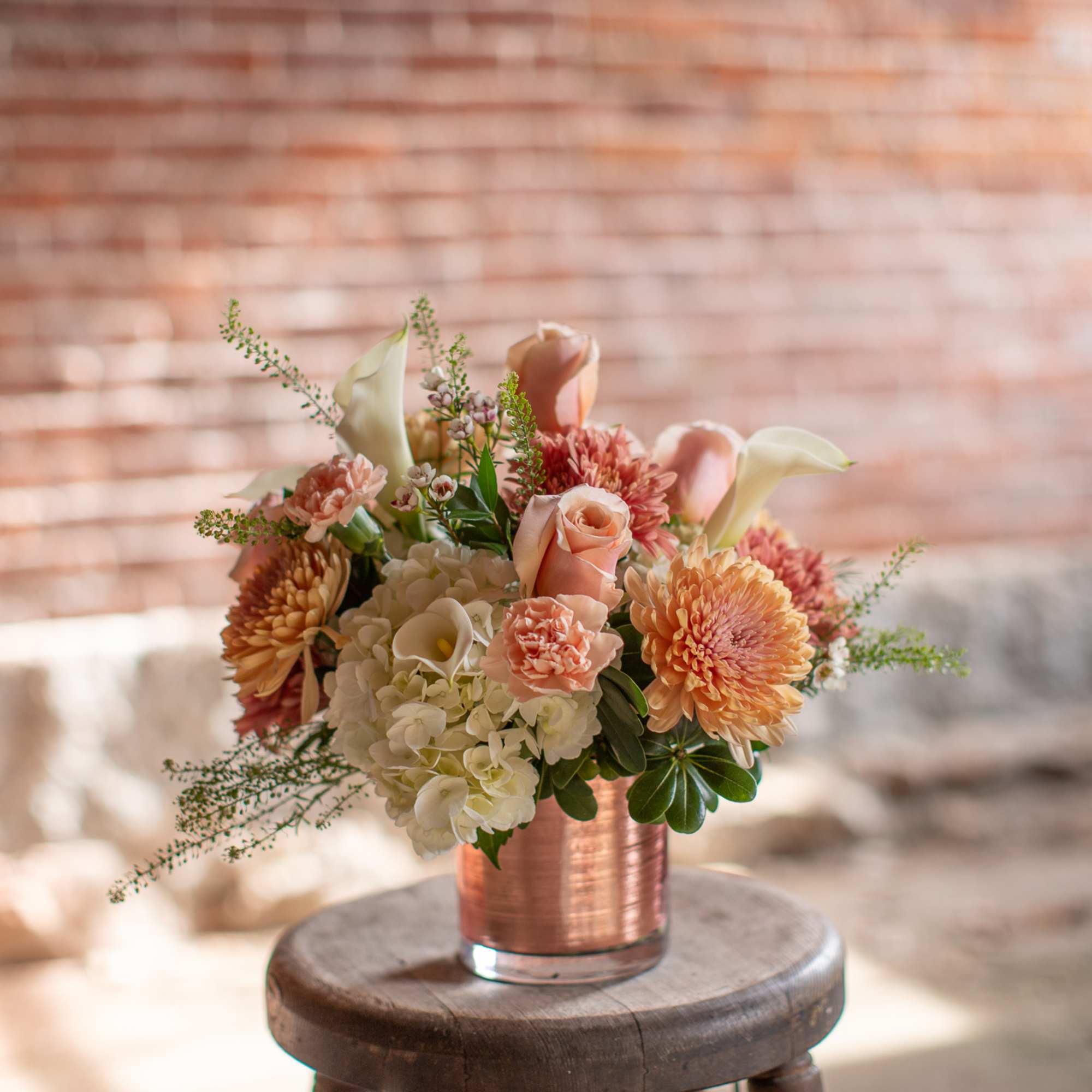 Peach and white floral arrangement in a copper vase
