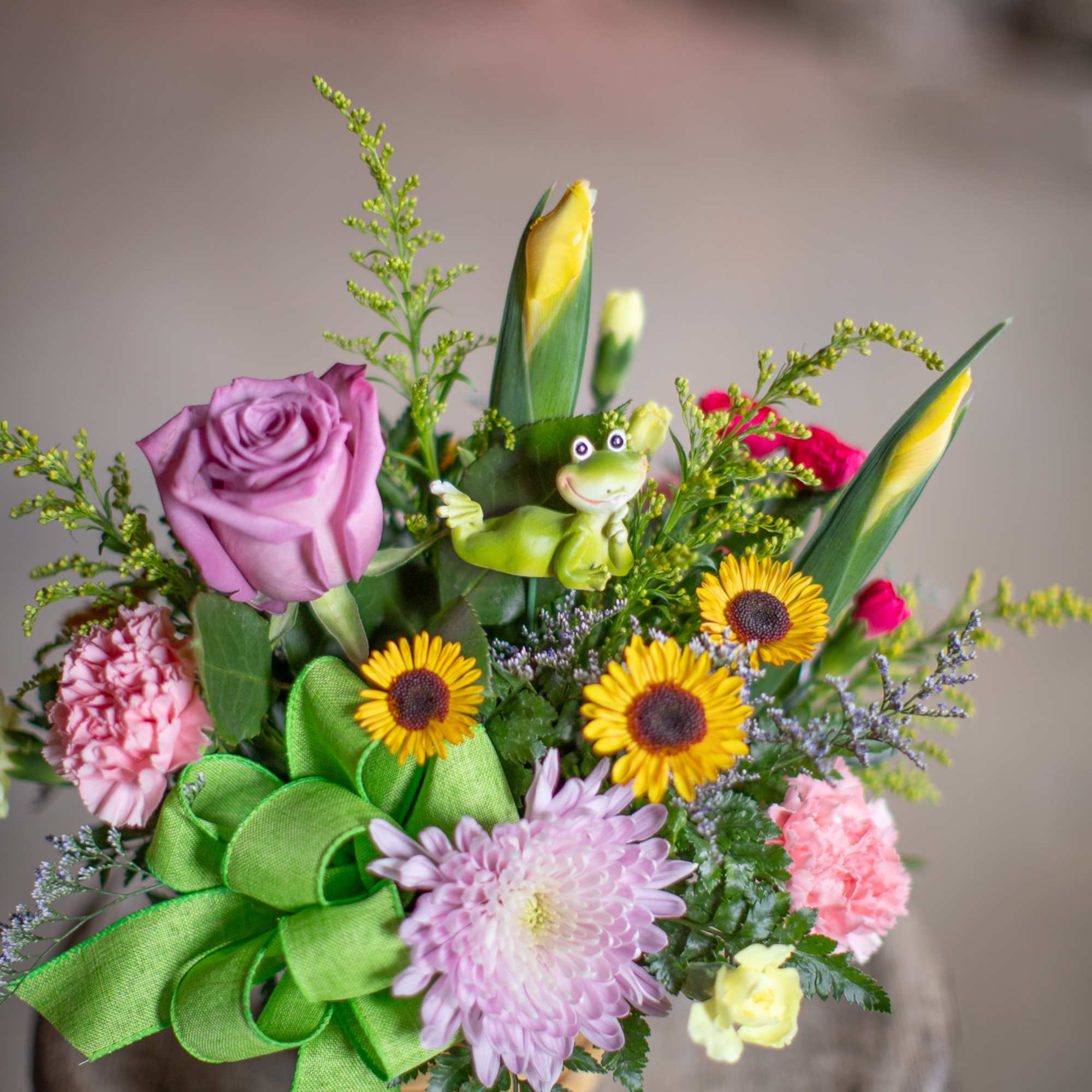 Mixed bouquet with roses, daisies, and a small frog figurine