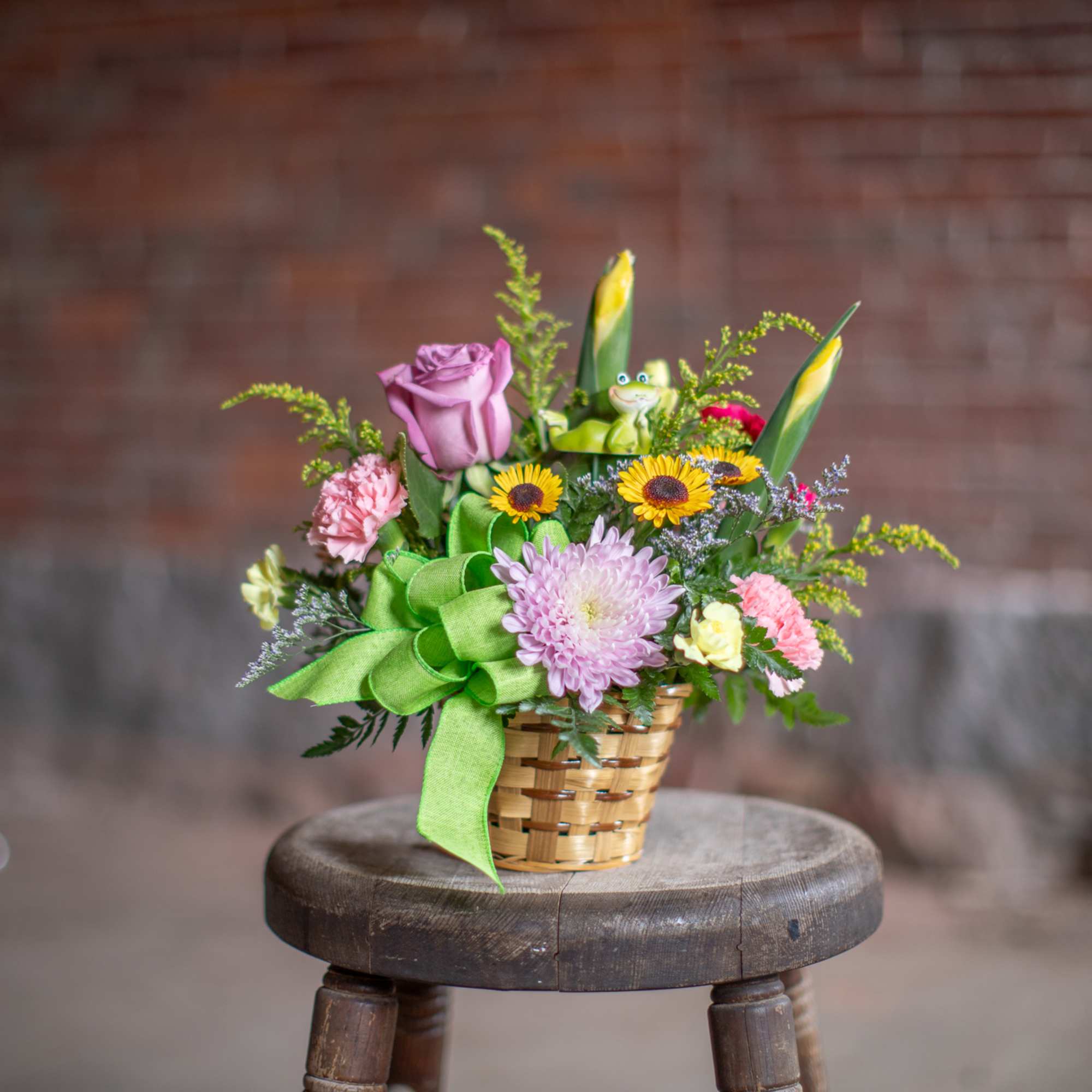 Mixed flower basket with a green ribbon on a stool