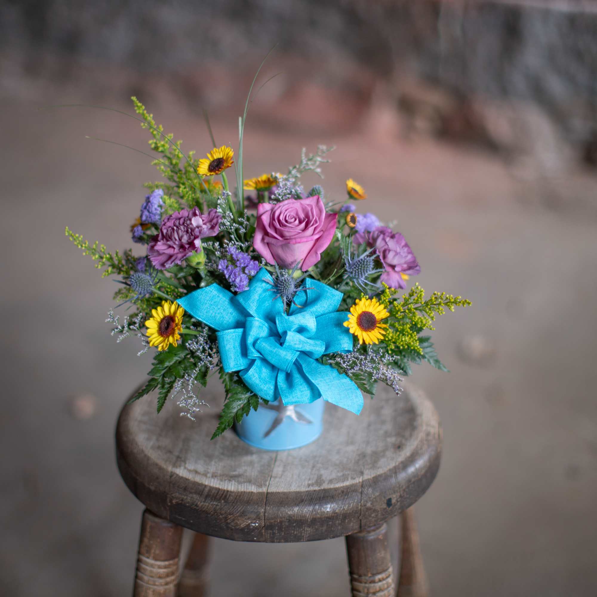 Small mixed bouquet in a blue container with a bright blue bow