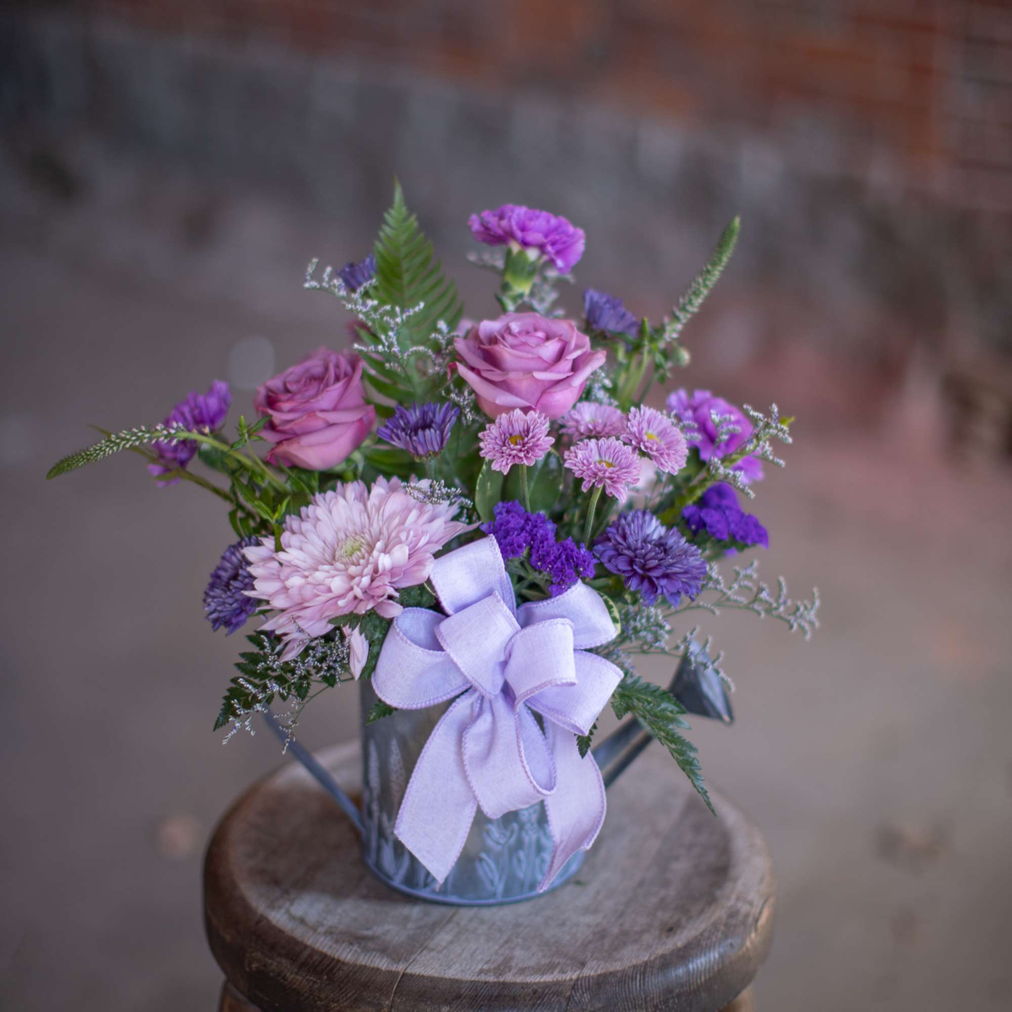 Lavender and purple bouquet in a metal pail with a ribbon