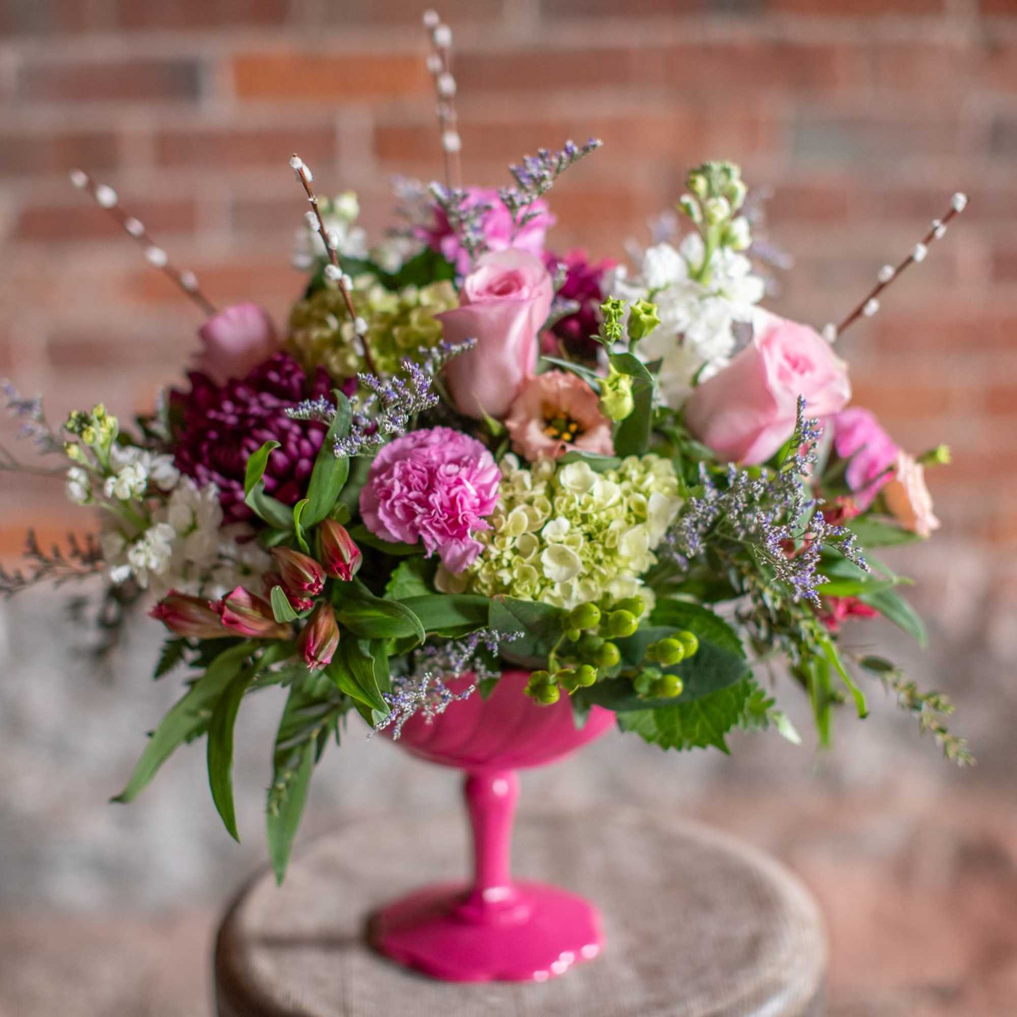 Pink and white mixed flower arrangement in a bright pink vase