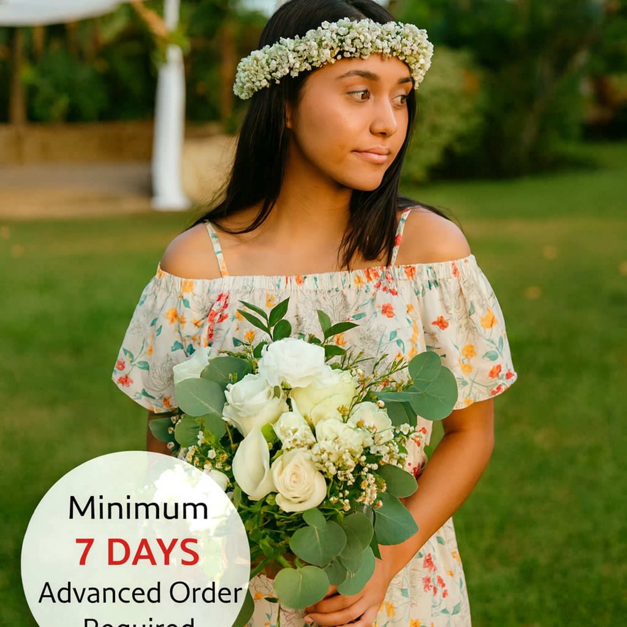 Young woman outdoors holding a white rose bouquet and wearing a white flower crown