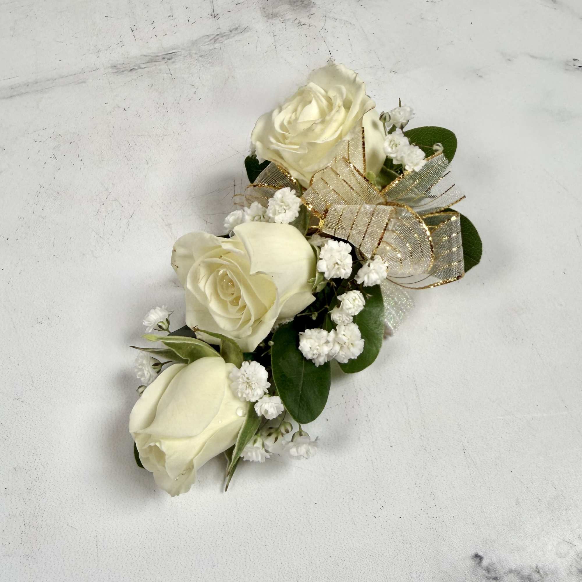 This wrist corsage features three white spray roses, babies breath and white, photo 3 of 3
