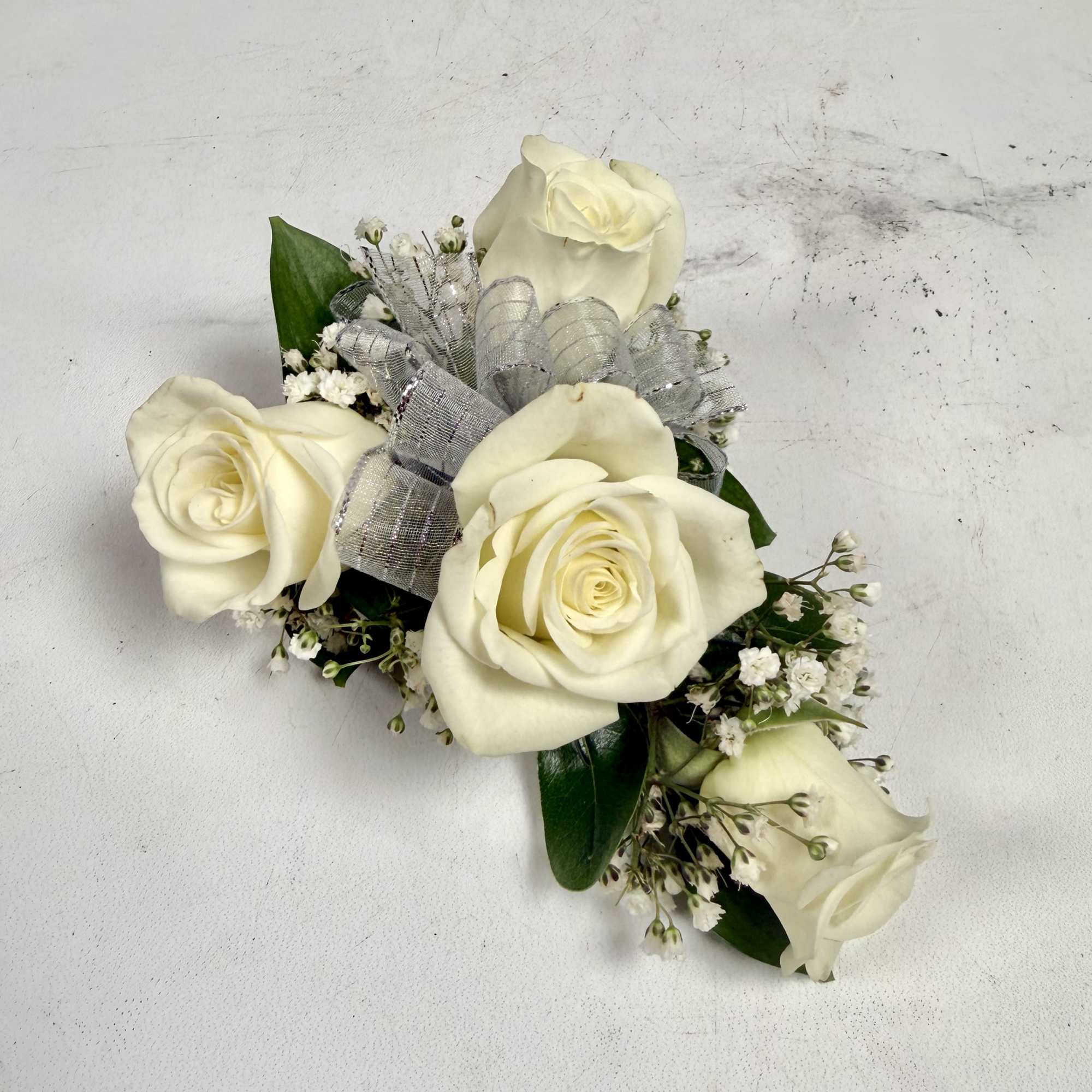 This wrist corsage features three white spray roses, babies breath and white, photo 2 of 3