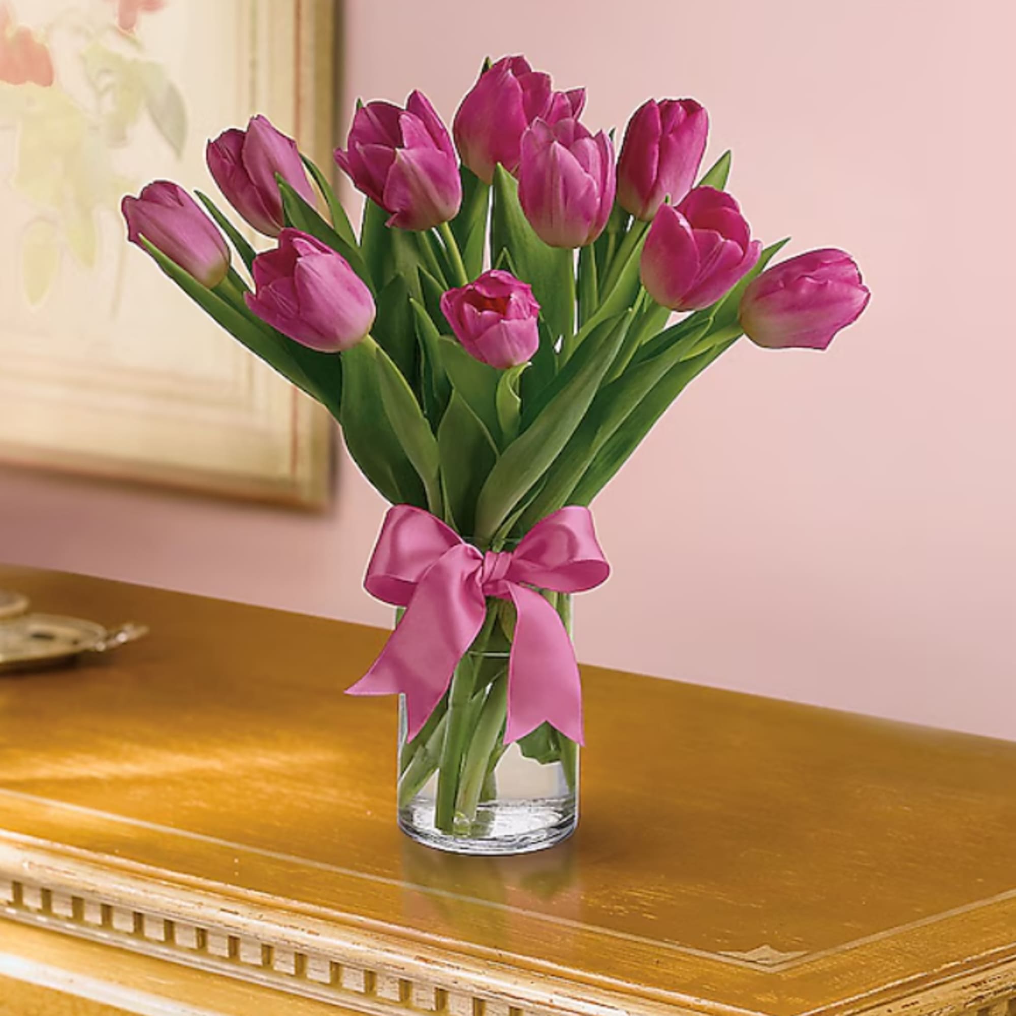 Pink tulips in a clear glass vase tied with a pink ribbon