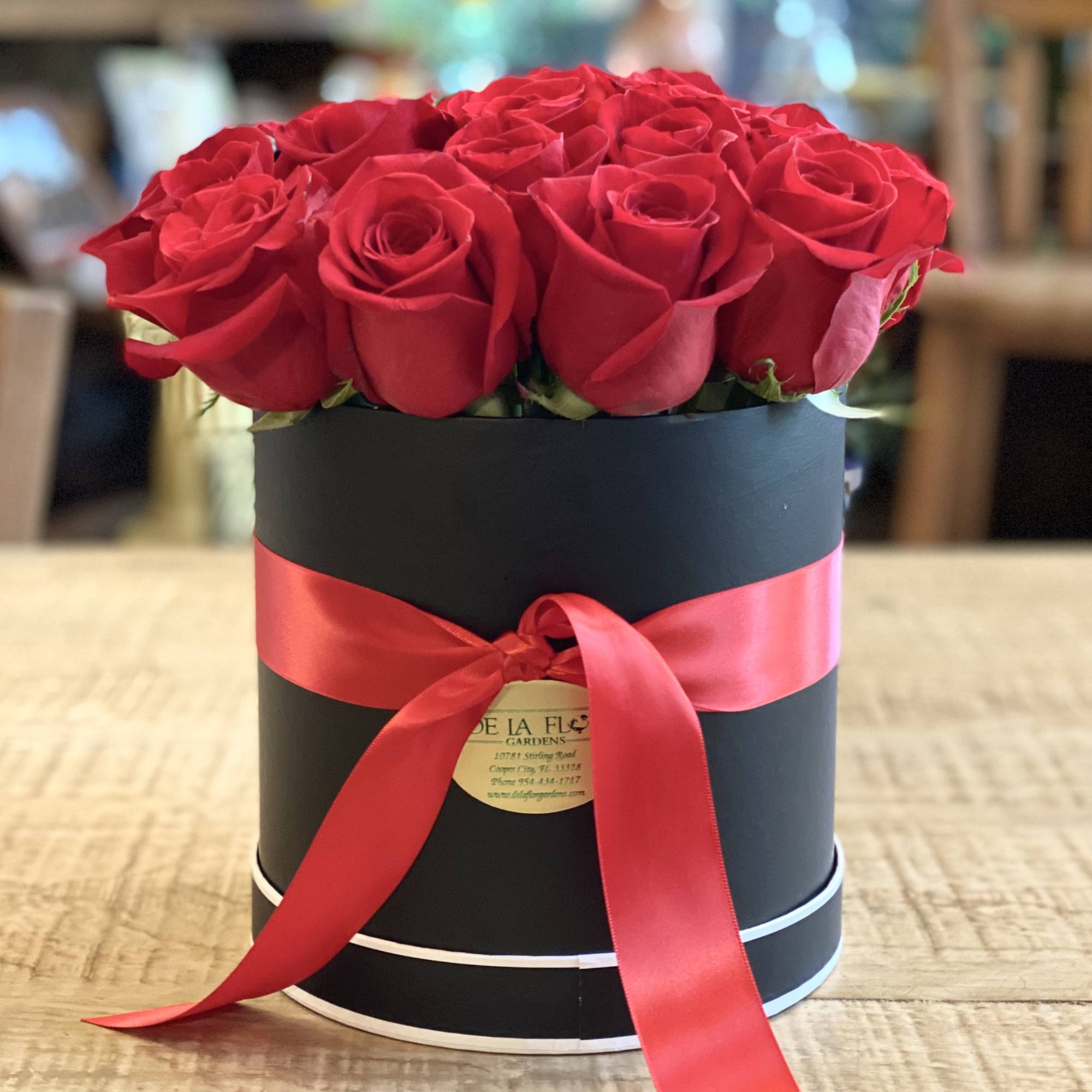 Red roses arranged in a black round box with a red ribbon, photo 2 of 2