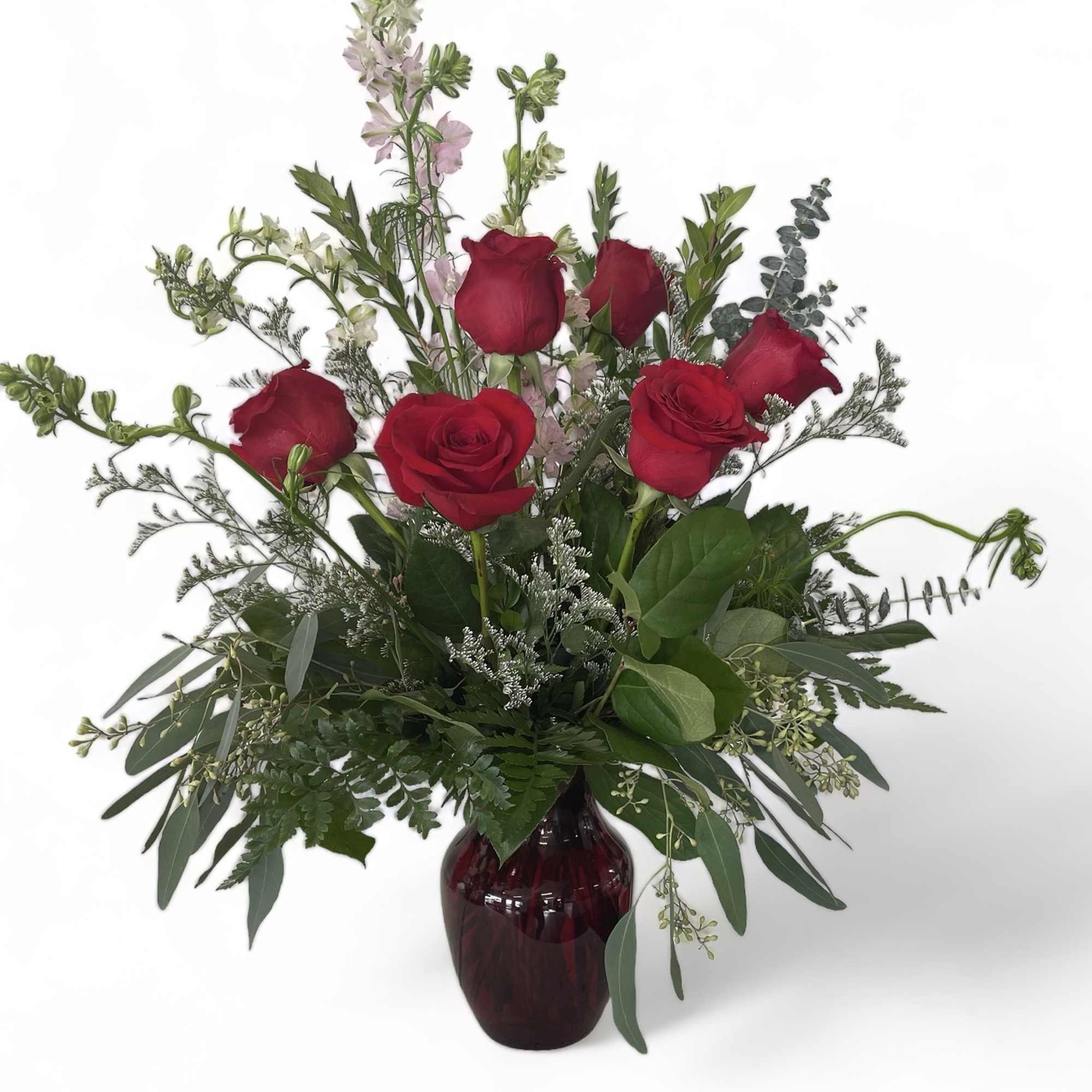 Red roses and mixed greenery in a dark glass vase