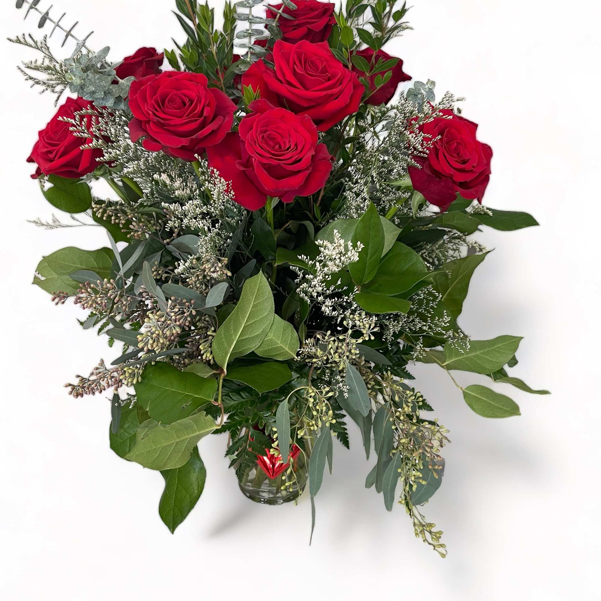 Red roses in a clear glass vase with mixed greenery