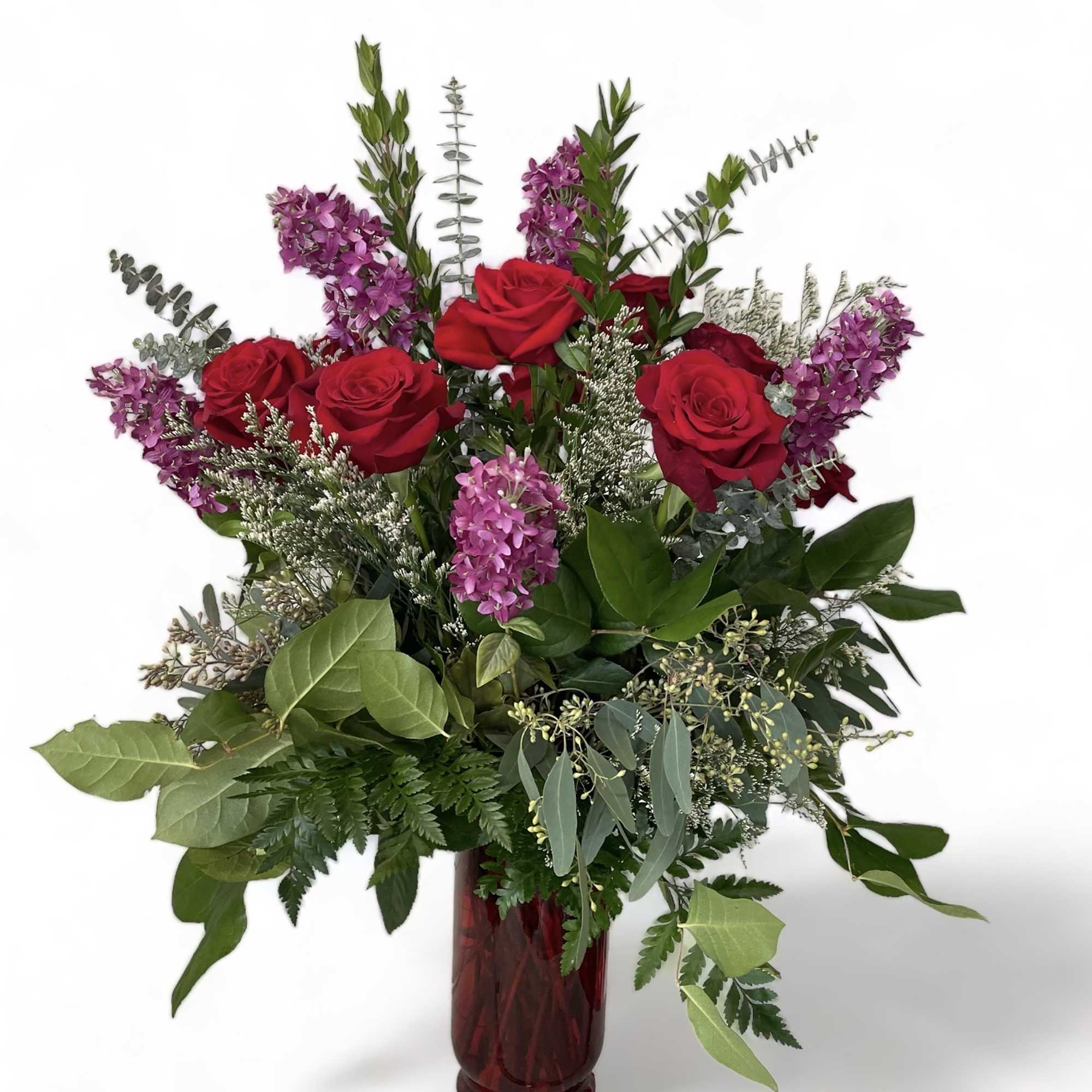 Red roses and purple flowers in a red glass vase