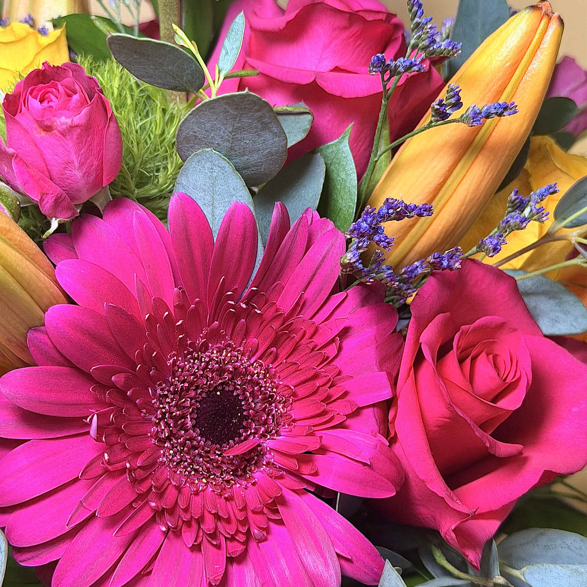Bright pink gerbera and roses with orange lilies in a bouquet