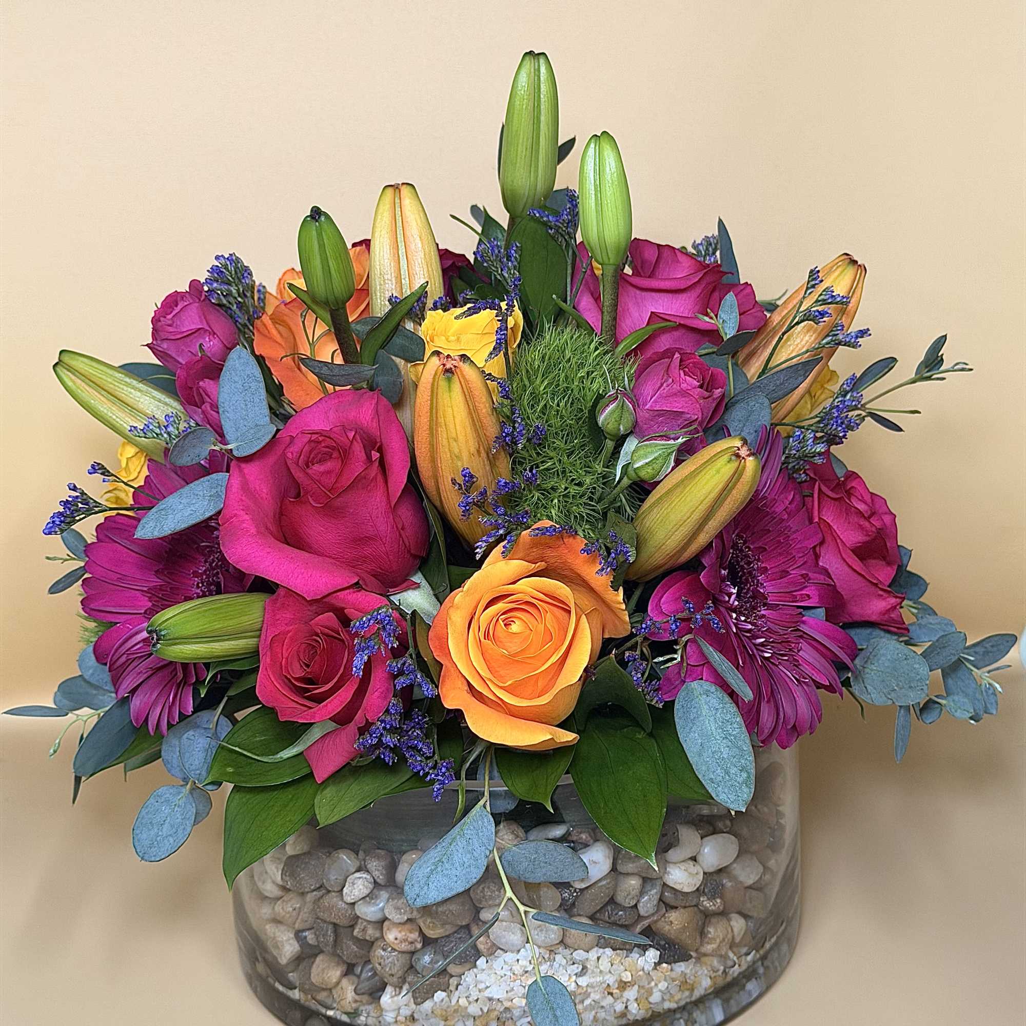 Bright mixed bouquet of roses and lilies in a glass bowl vase
