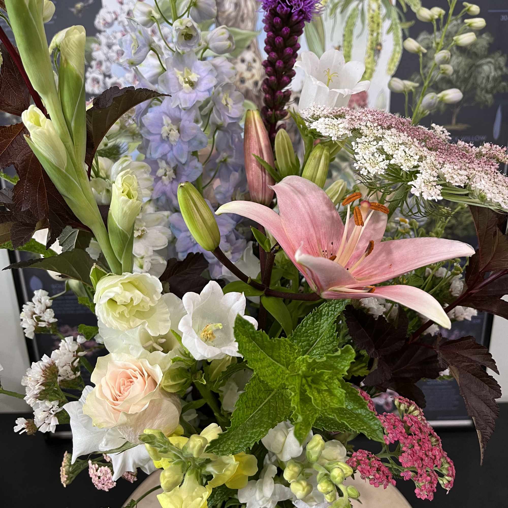 Mixed bouquet with pink lily, roses, and pale blue flowers in a vase