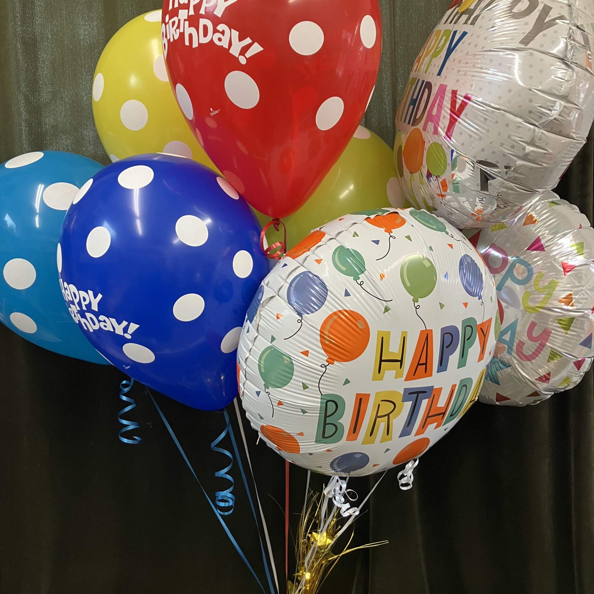 Cluster of colorful birthday balloons with polka dots and printed messages