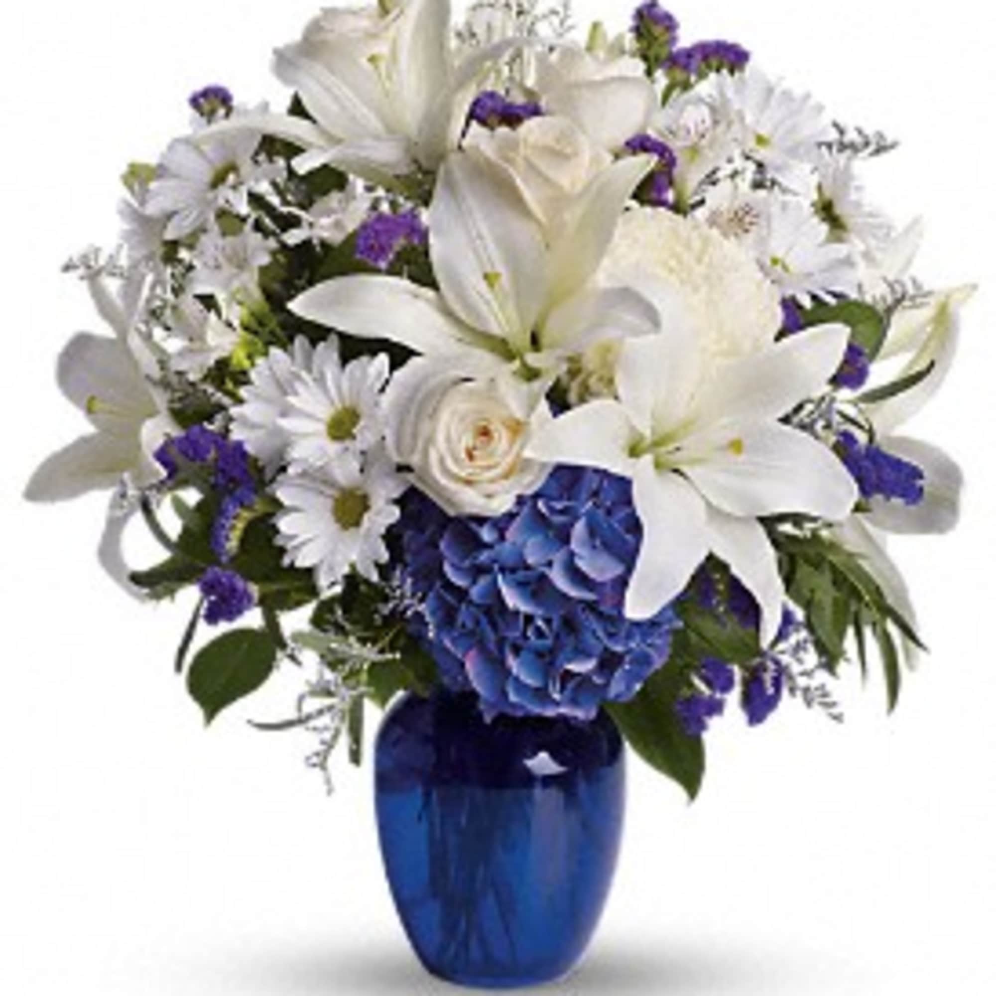 Mixed arrangement of white lilies, roses and daisies with blue hydrangea in a dark blue glass vase