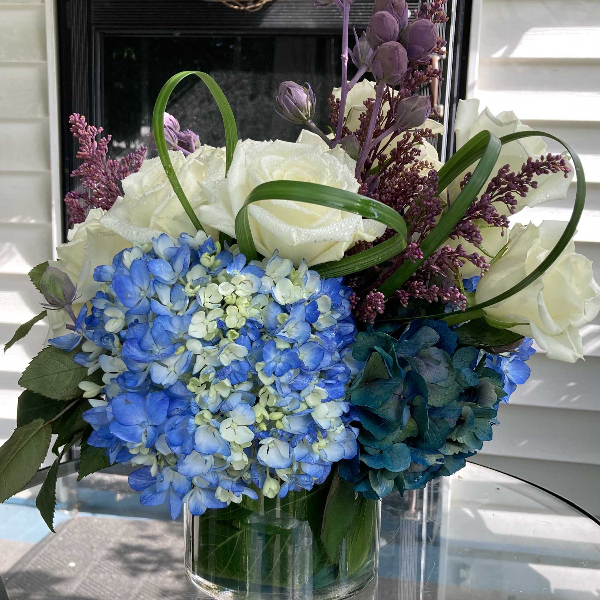 Blue hydrangeas and white roses in a clear glass vase