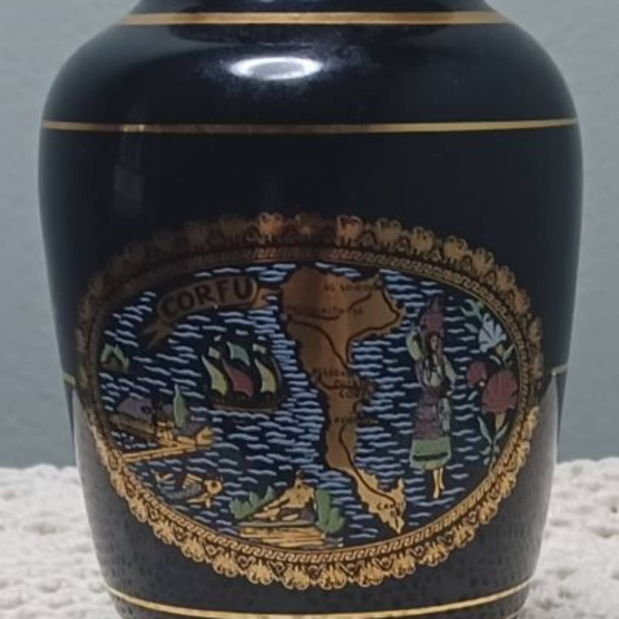 Black decorative urn with gold trim and a colorful emblem