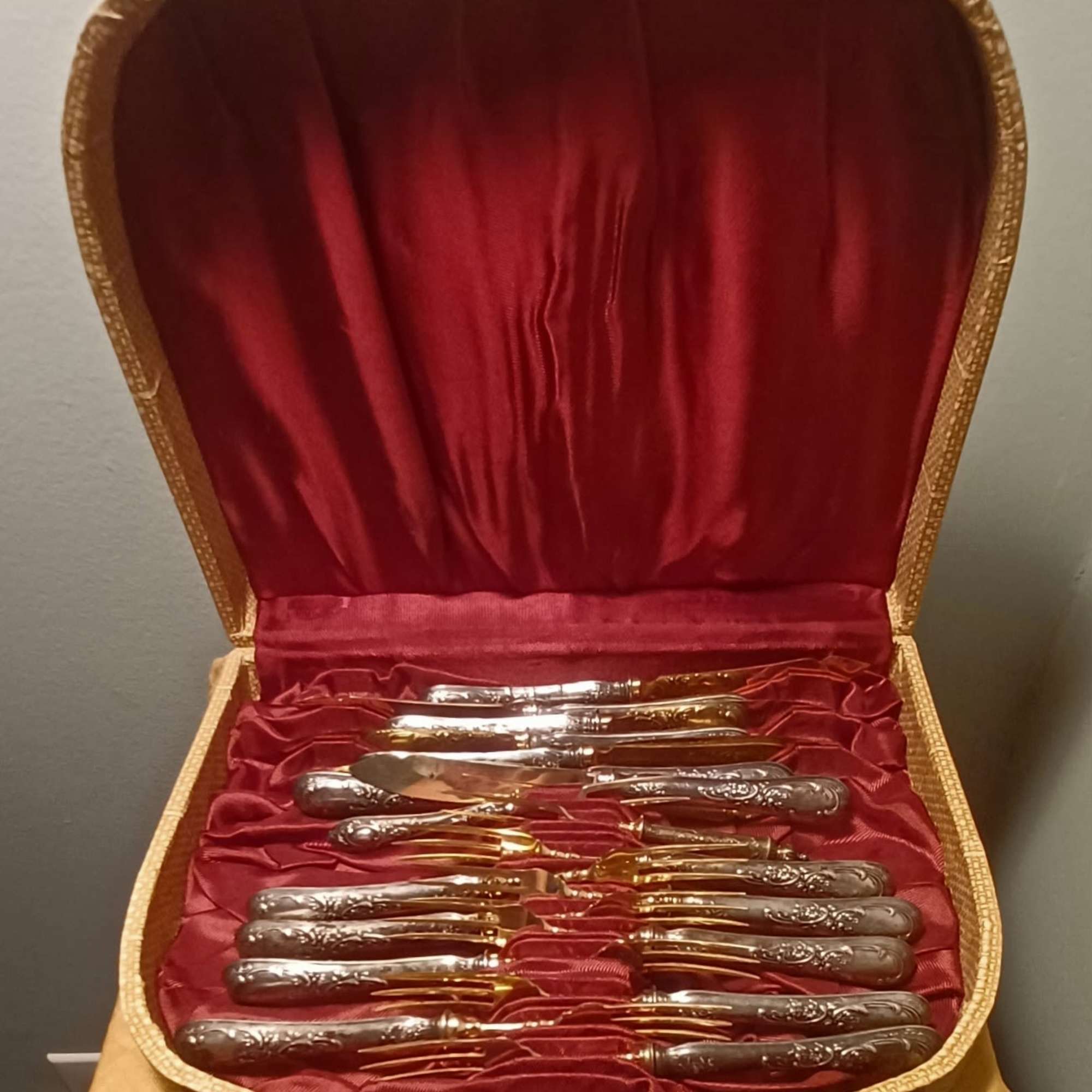 Open case holding a set of silver and gold flatware