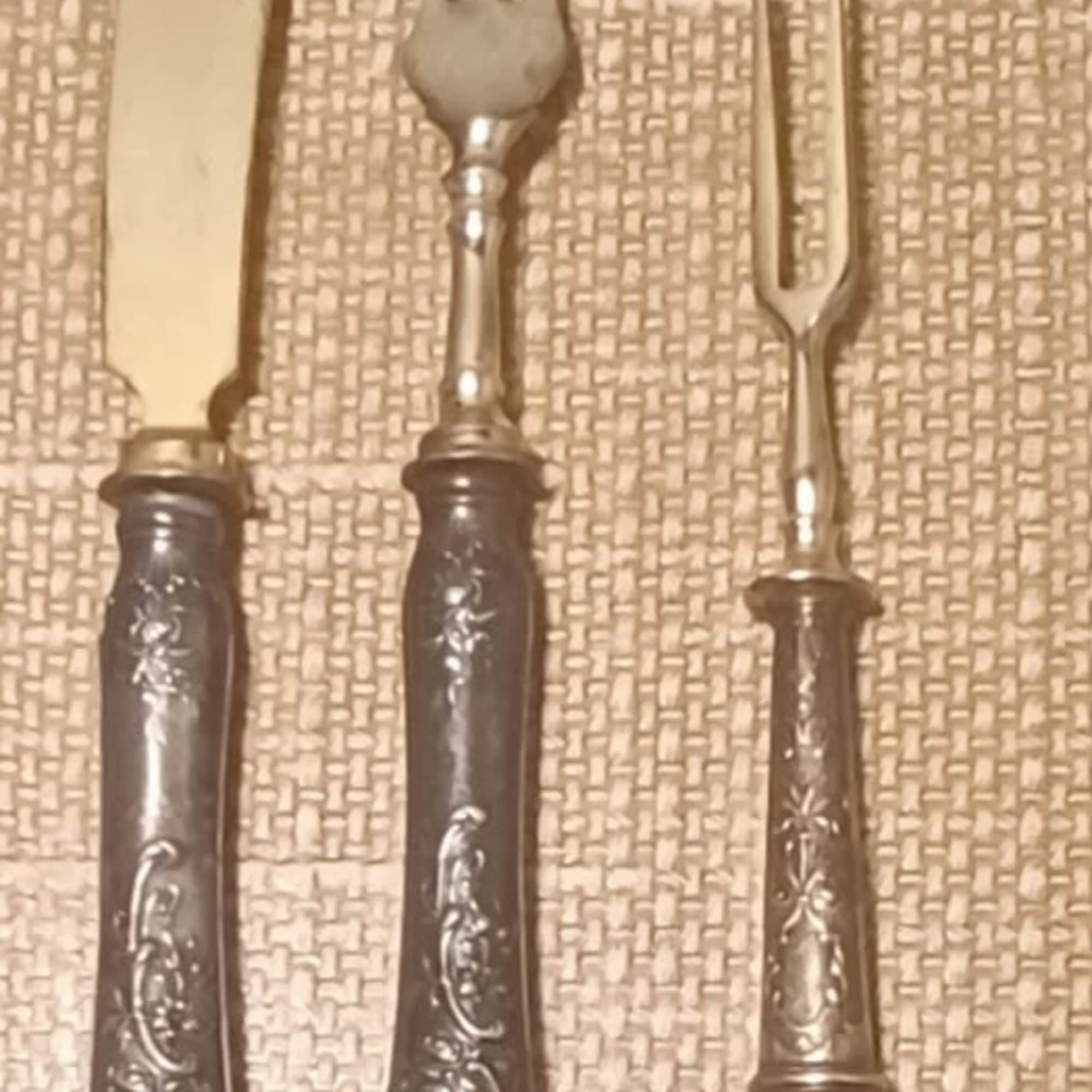 Three vintage silver serving pieces on a woven surface