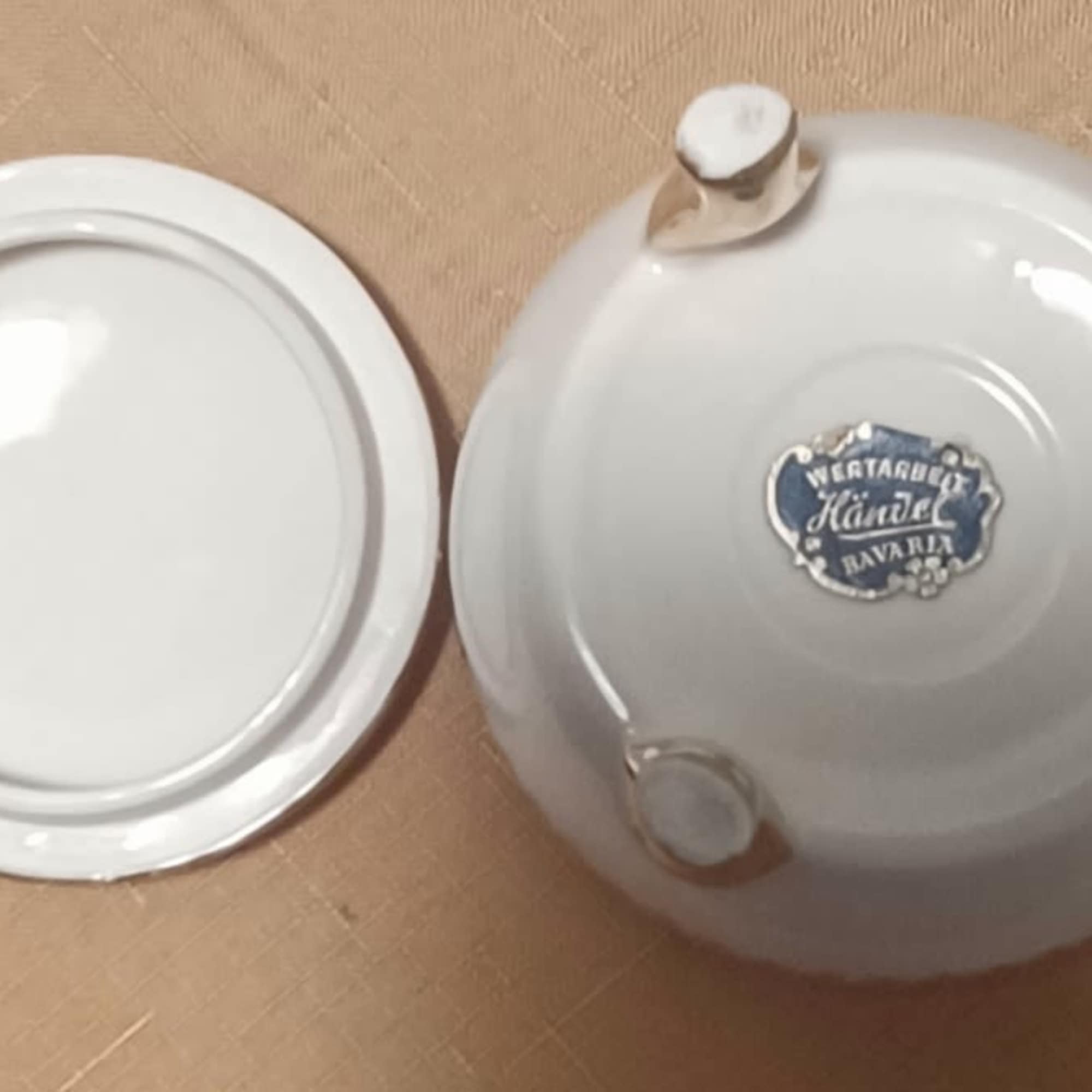 Two white ceramic lids or dishes on a tan surface