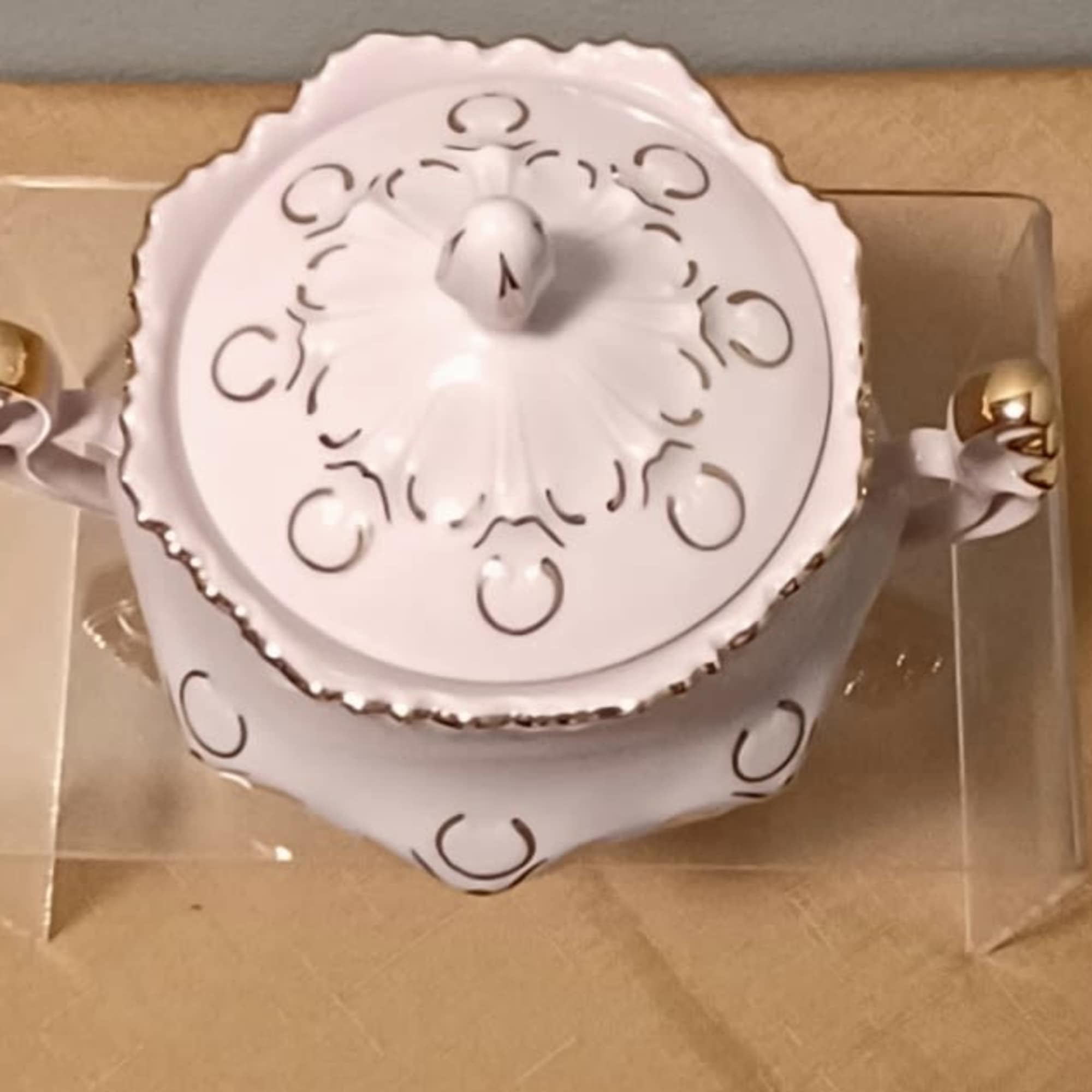 White lidded ceramic serving dish with gold handles in a clear box
