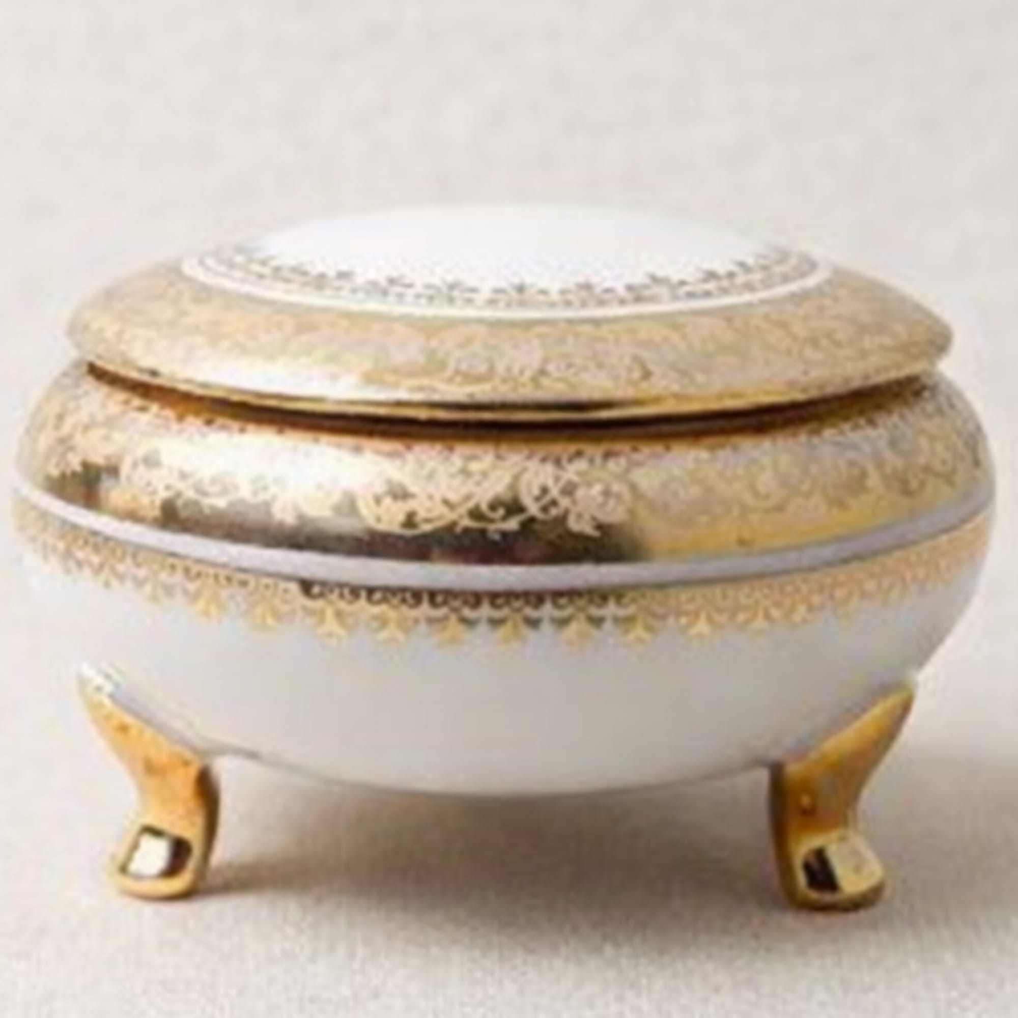 Decorative white and gold lidded trinket box on small feet