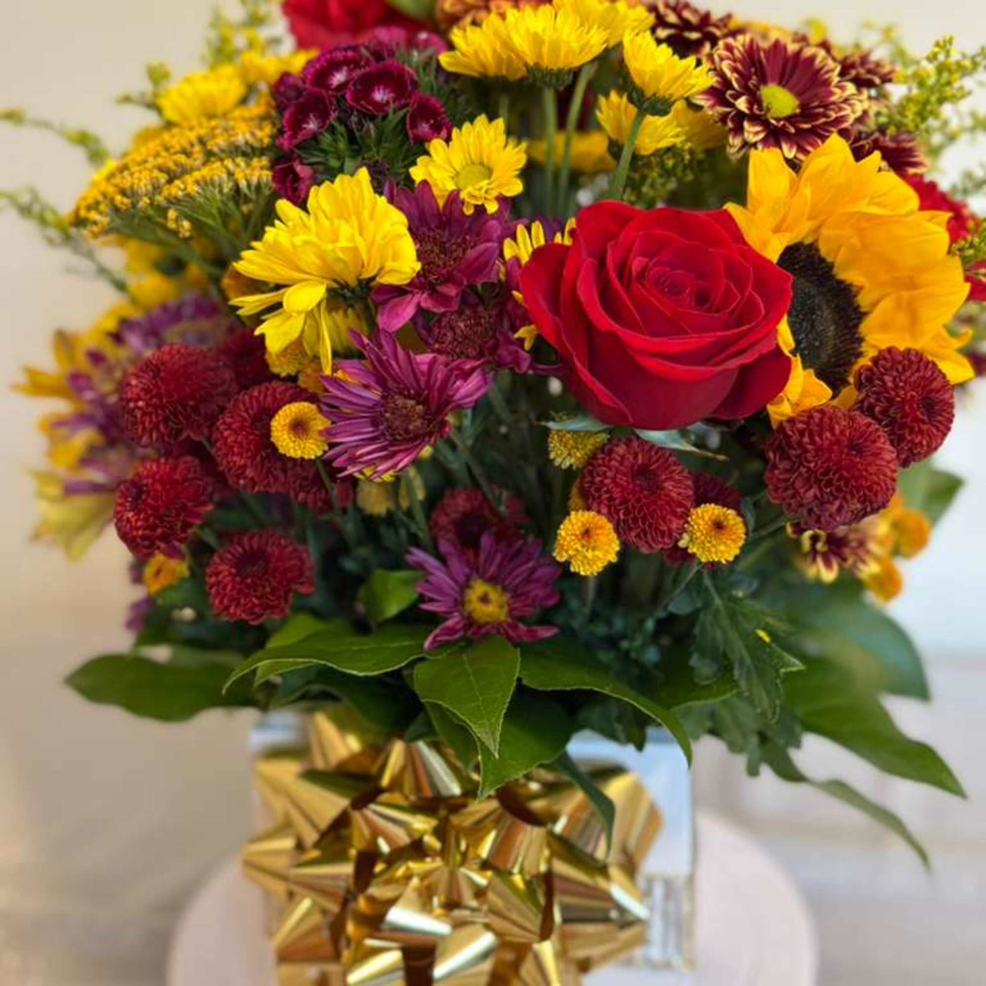 Mixed bouquet with a red rose and yellow sunflowers in a gift box