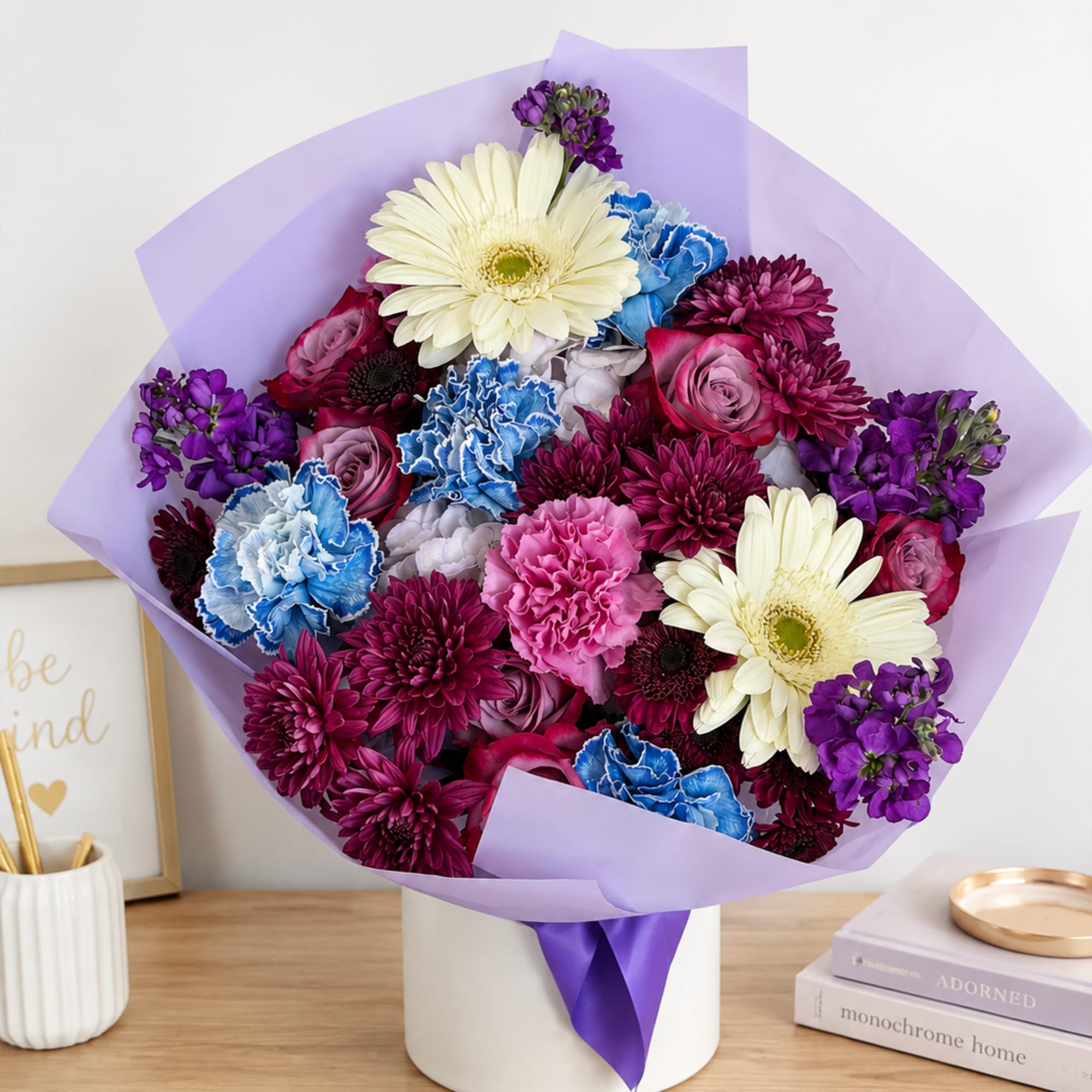 Mixed bouquet of purple, pink, blue, and white flowers in a white box