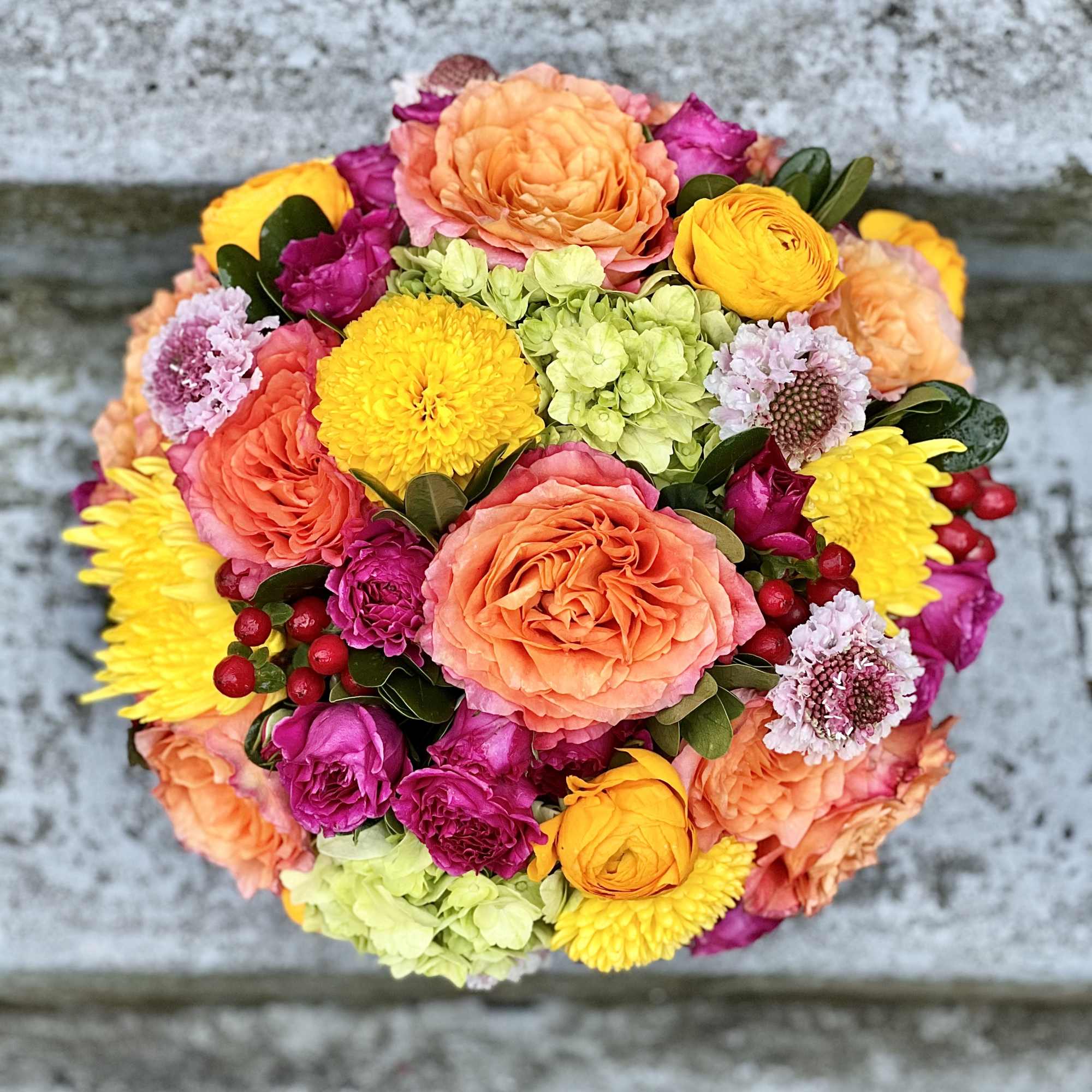 Round bouquet of peach, yellow, pink, and green flowers