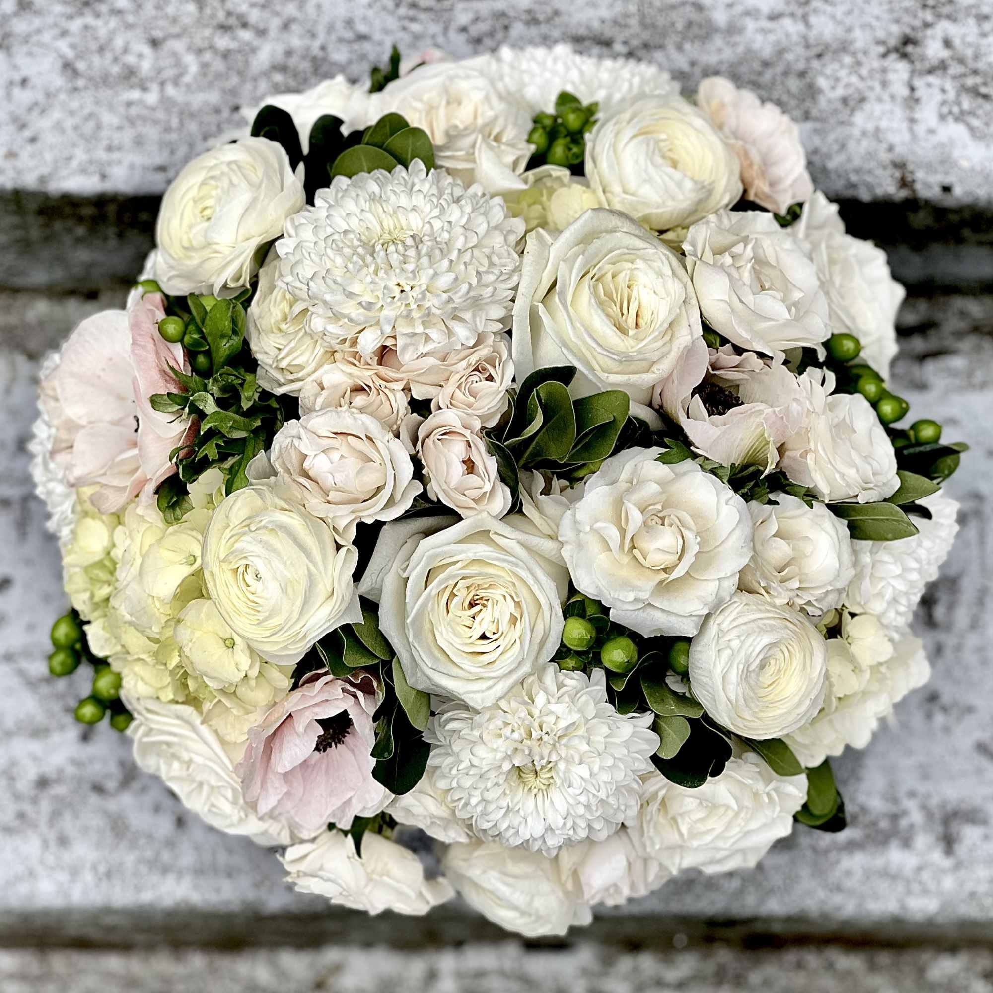 Round bouquet of white and blush flowers with green accents