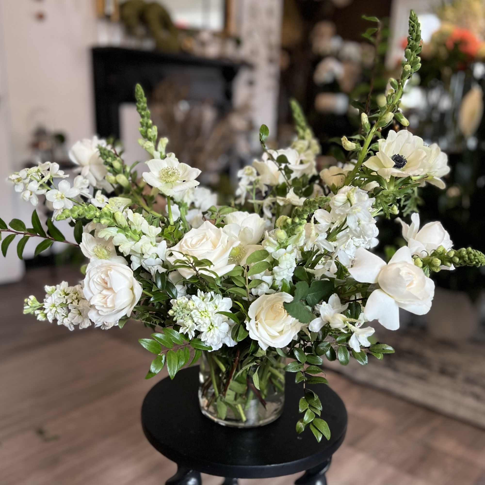 White roses and anemones arranged in a clear glass vase