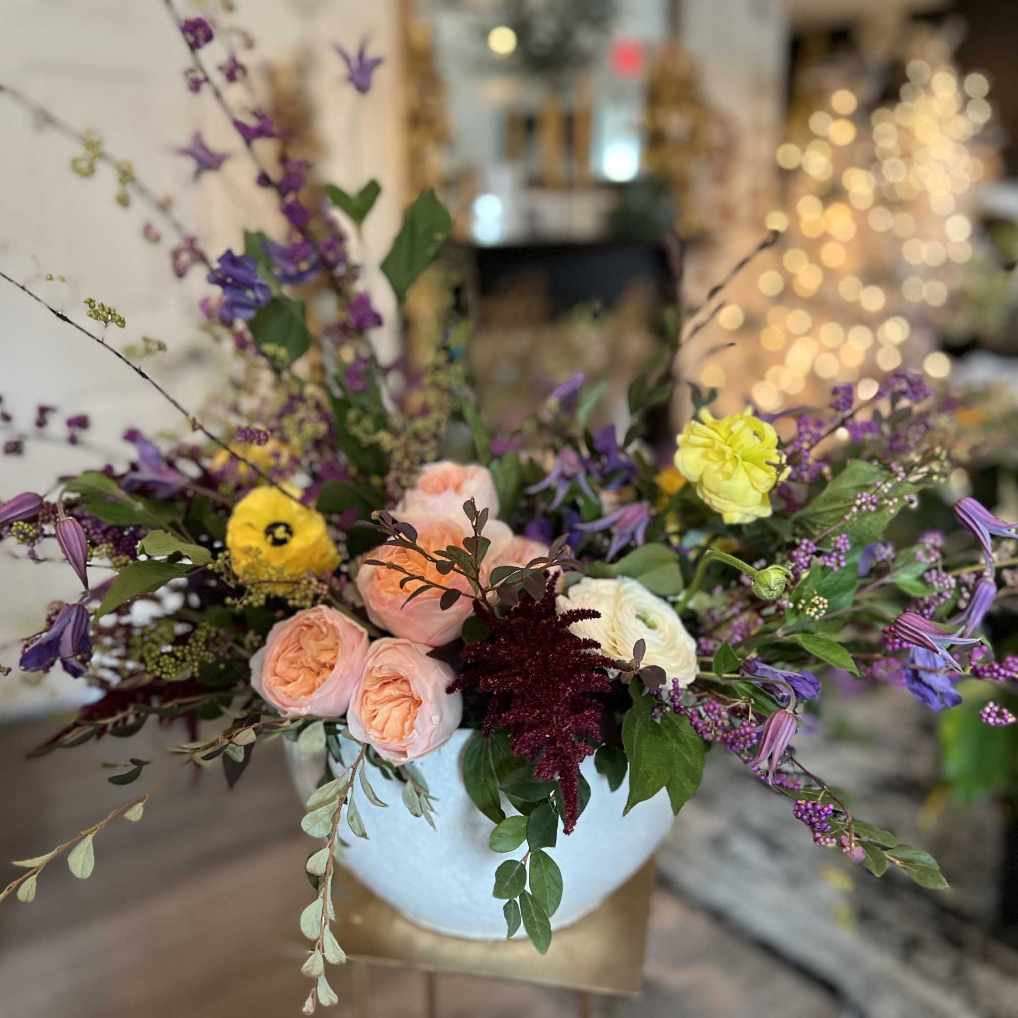 Mixed bouquet in a light blue vase with pink, purple, yellow, and white blooms