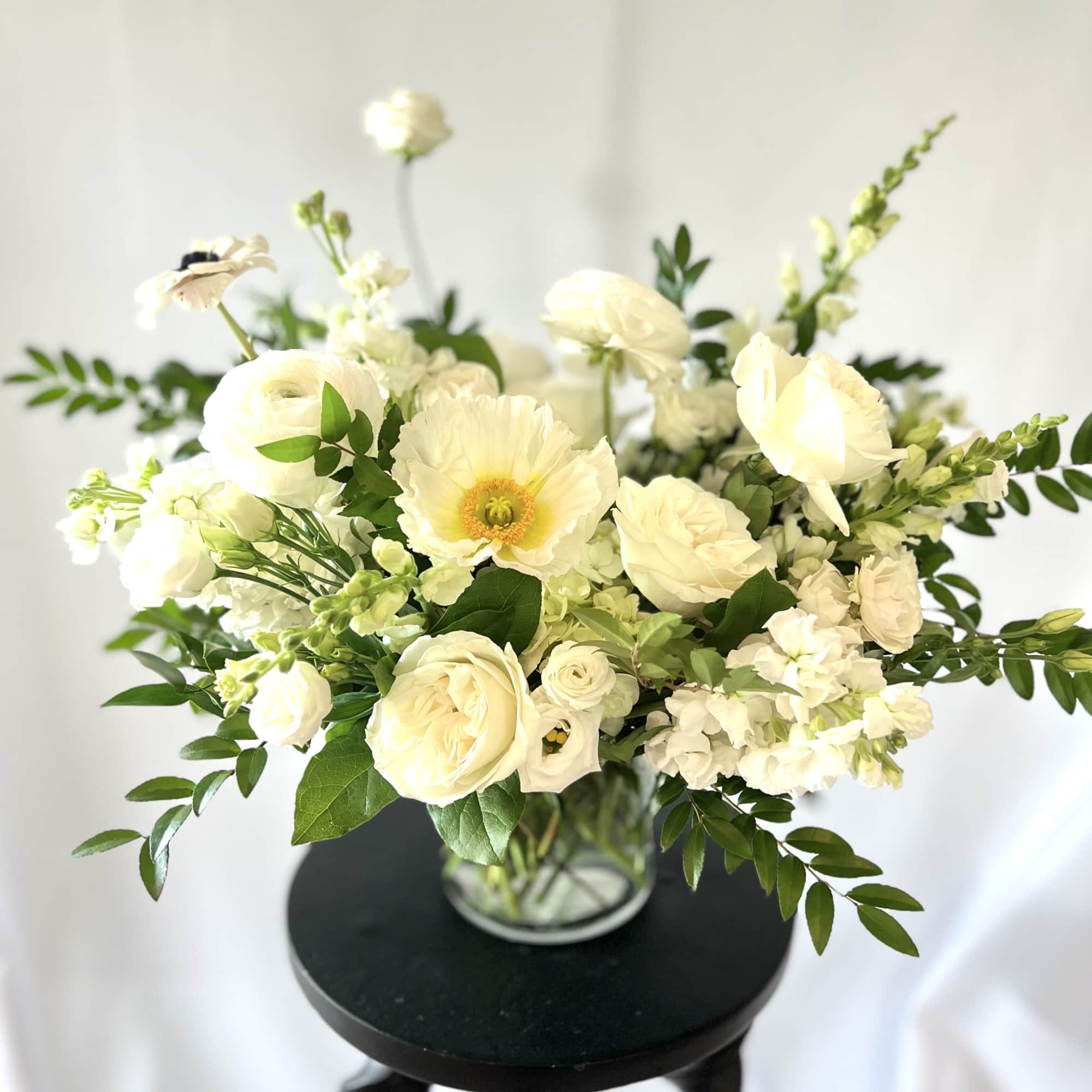 White floral arrangement in a clear glass vase with mixed blooms