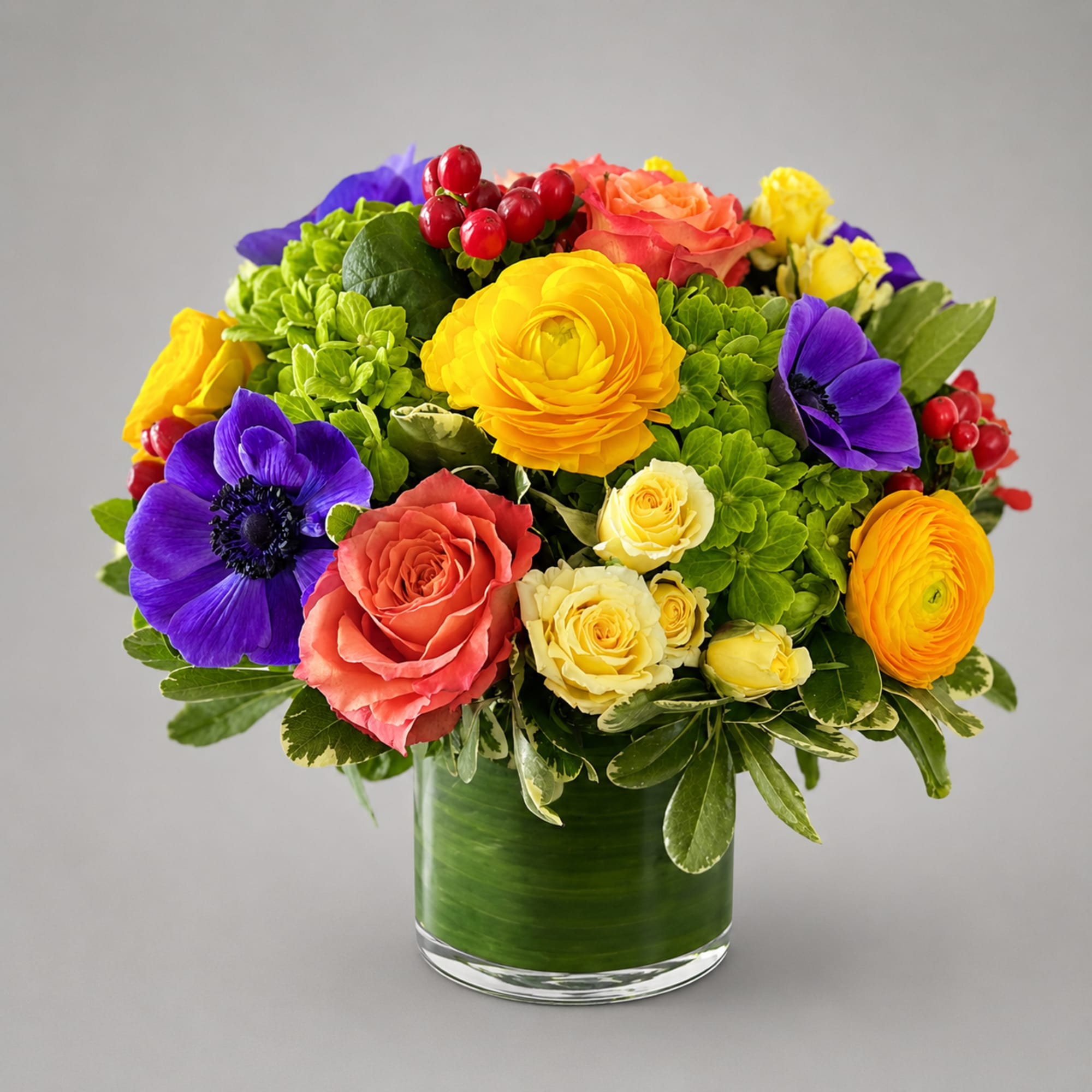 Colorful bouquet of roses and anemones in a glass vase