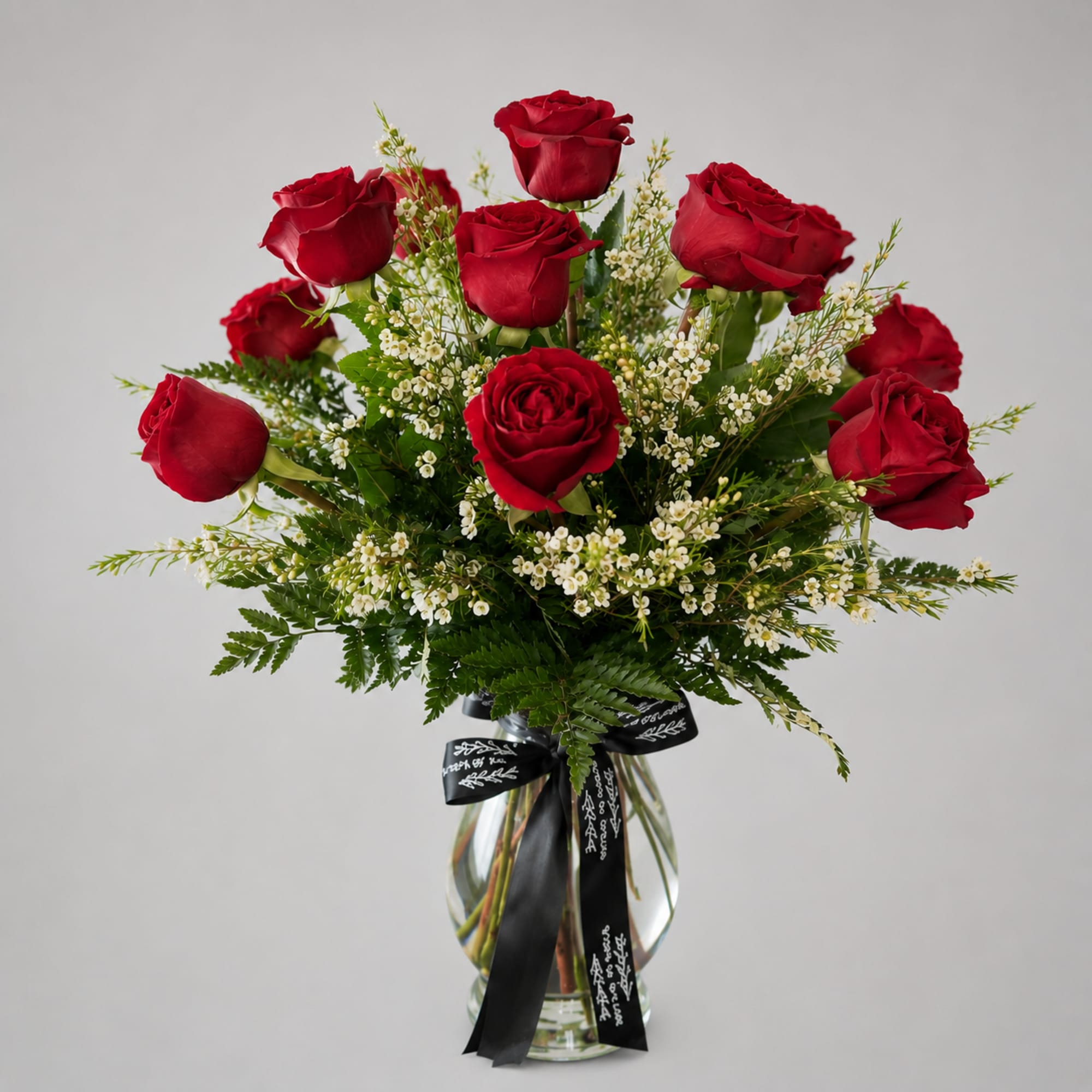 Red roses arranged in a clear glass vase with white filler flowers
