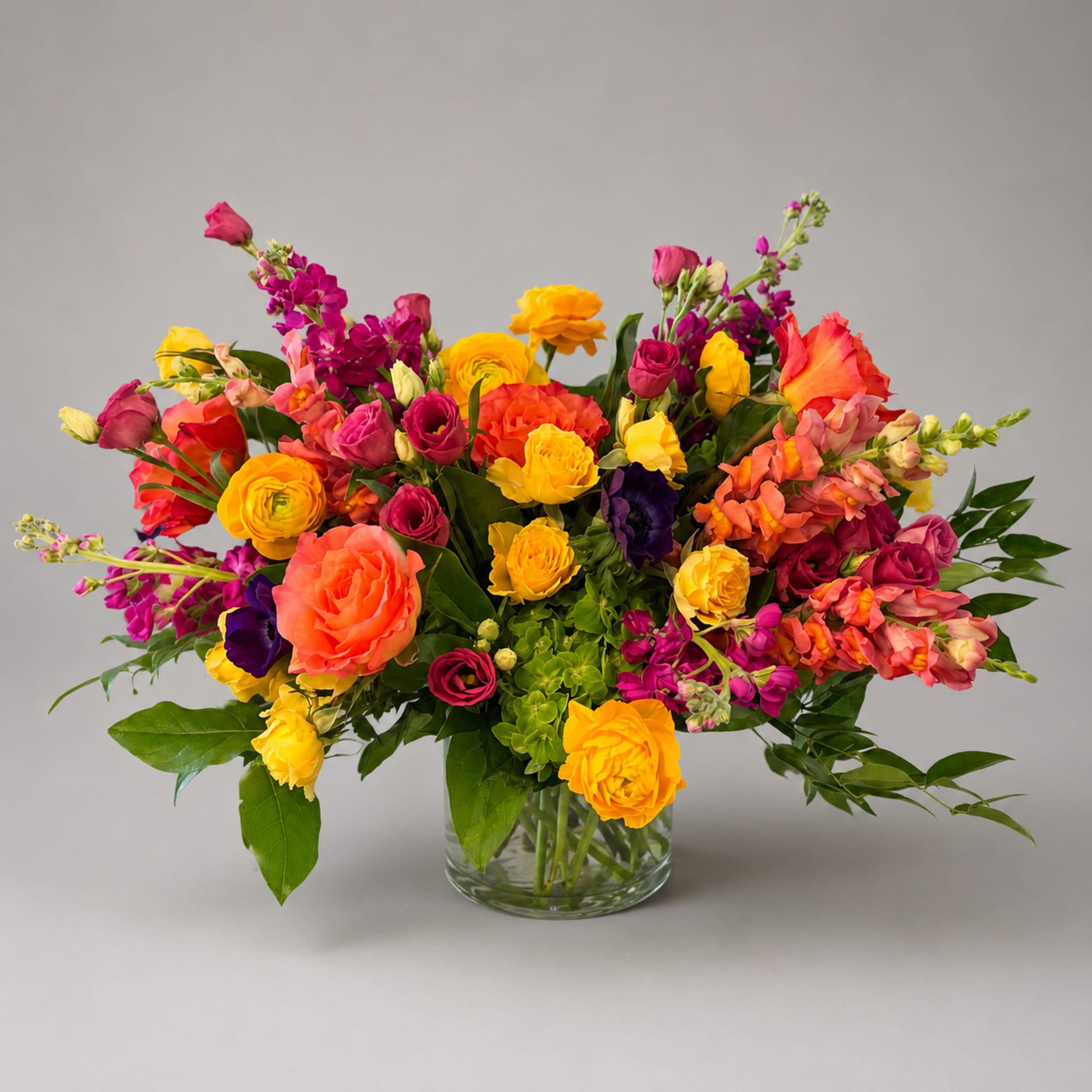 Bright mixed bouquet of roses and other flowers in a clear glass vase
