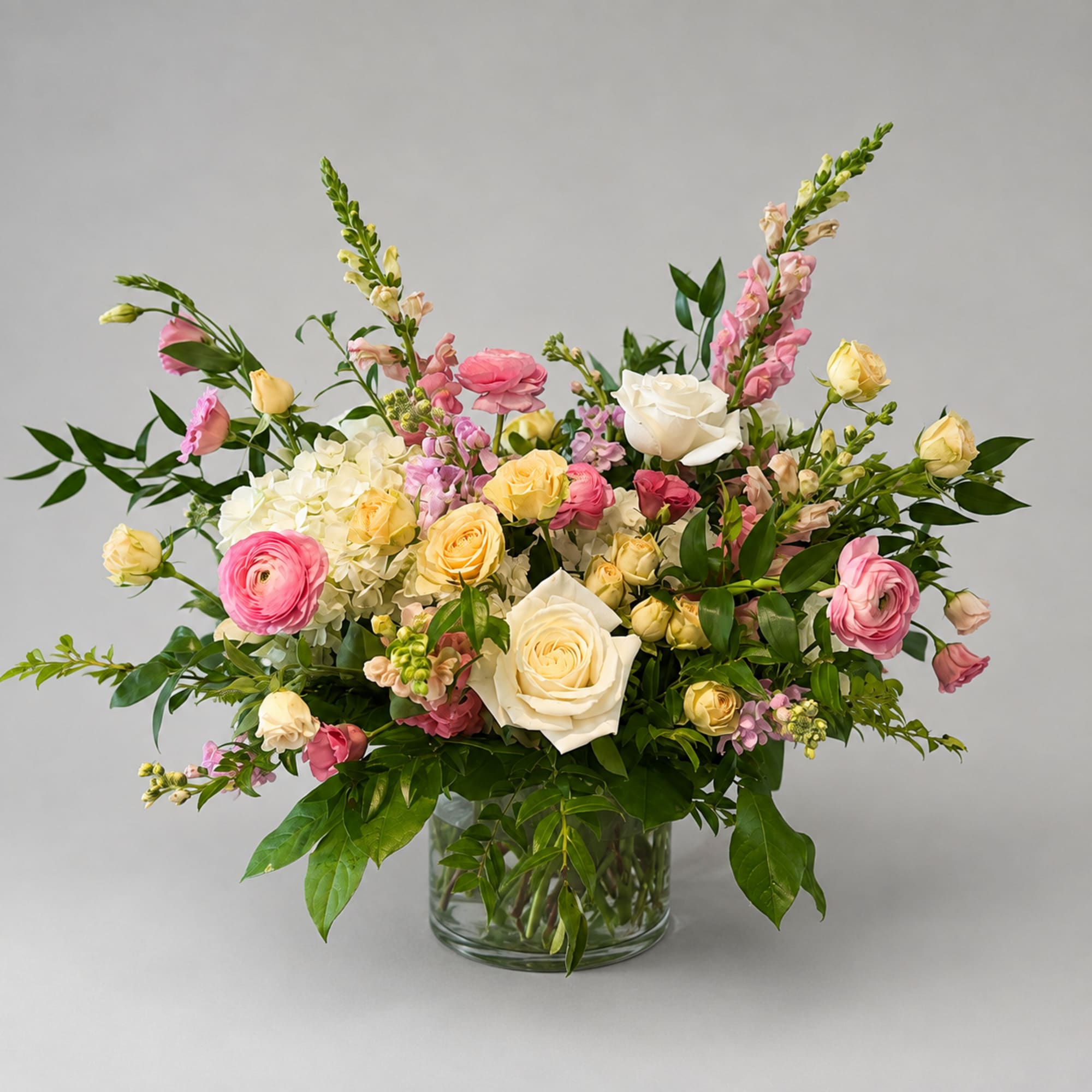 Mixed bouquet of pink and cream flowers in a glass vase