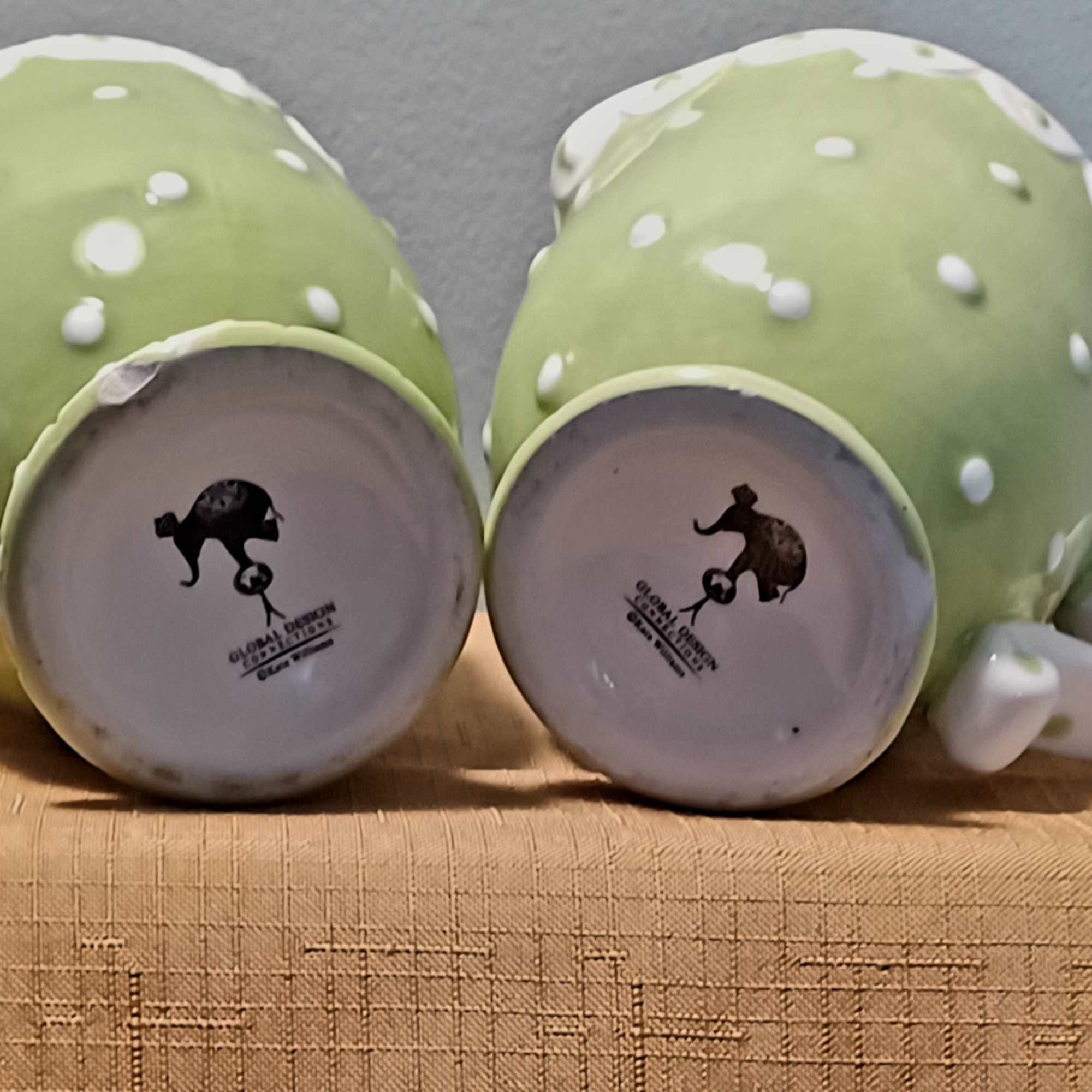 Two green polka-dot ceramic mugs lying on their sides