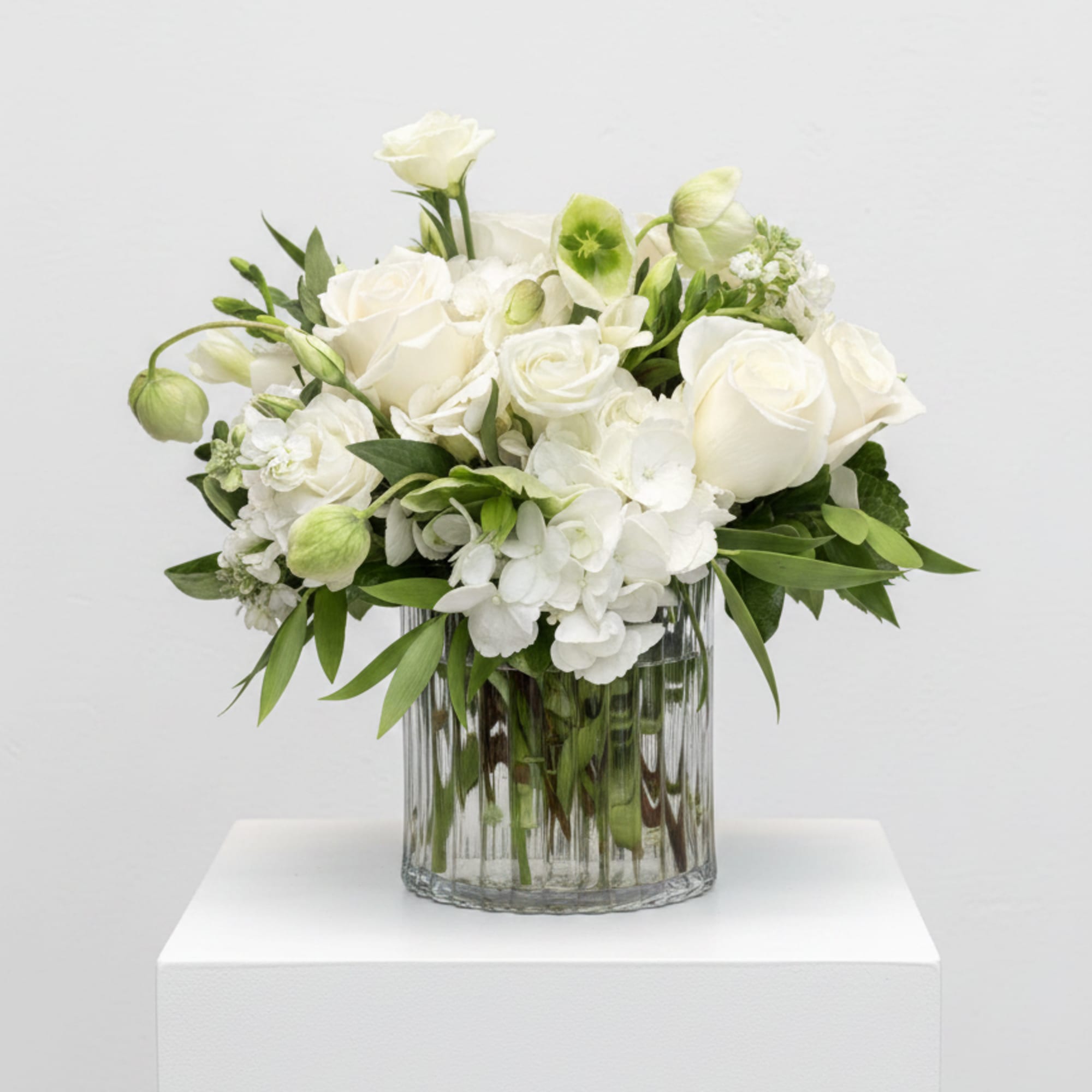 White roses and hydrangeas arranged in a clear glass vase