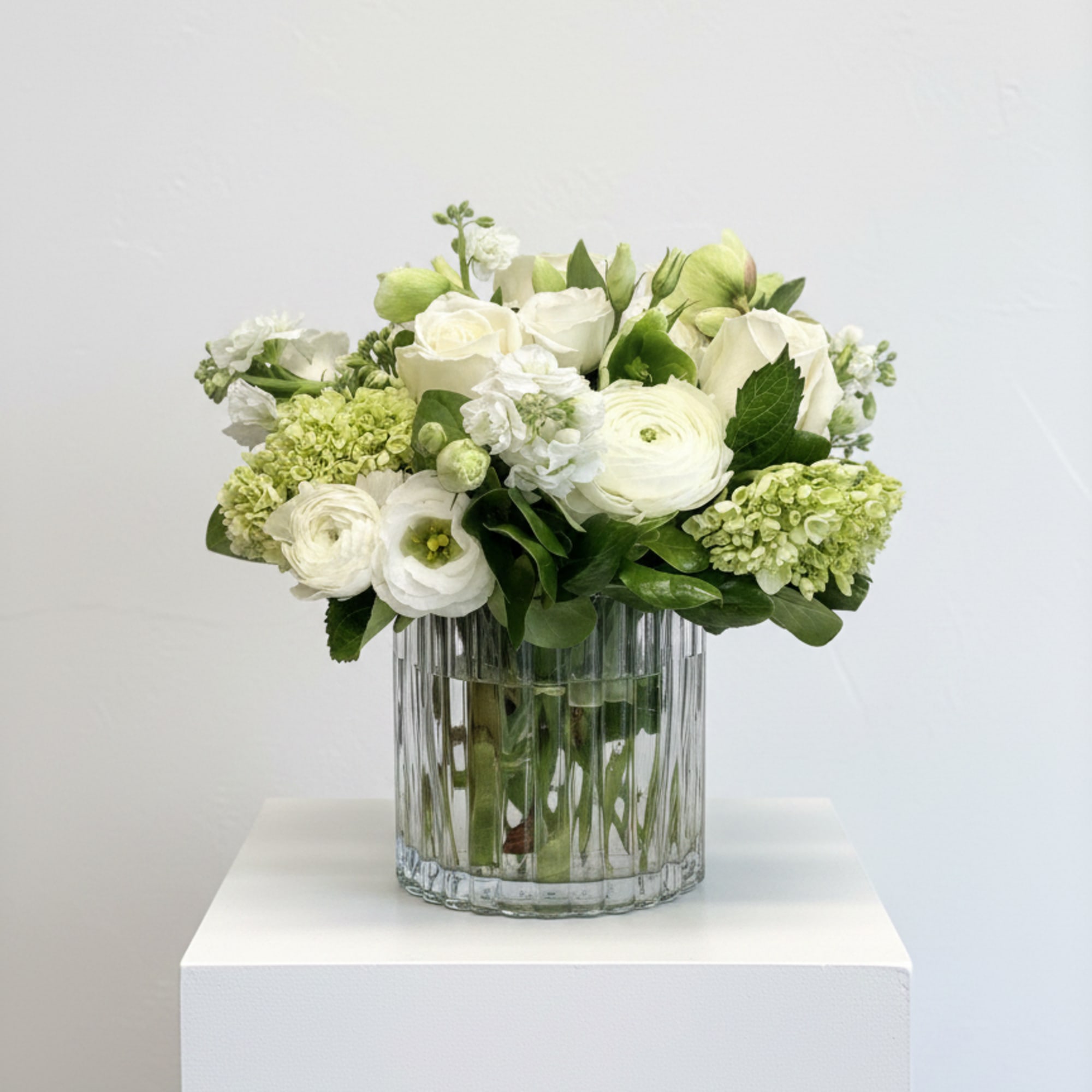 White and pale green floral arrangement in a clear glass vase