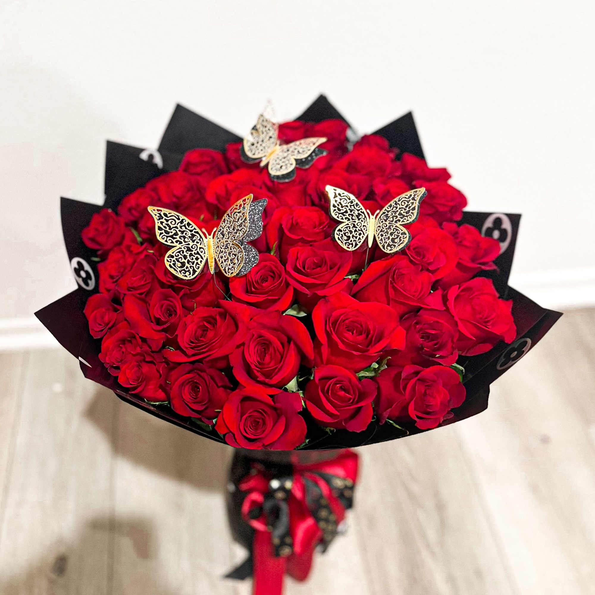 Bouquet of red roses with butterfly picks and black wrapping