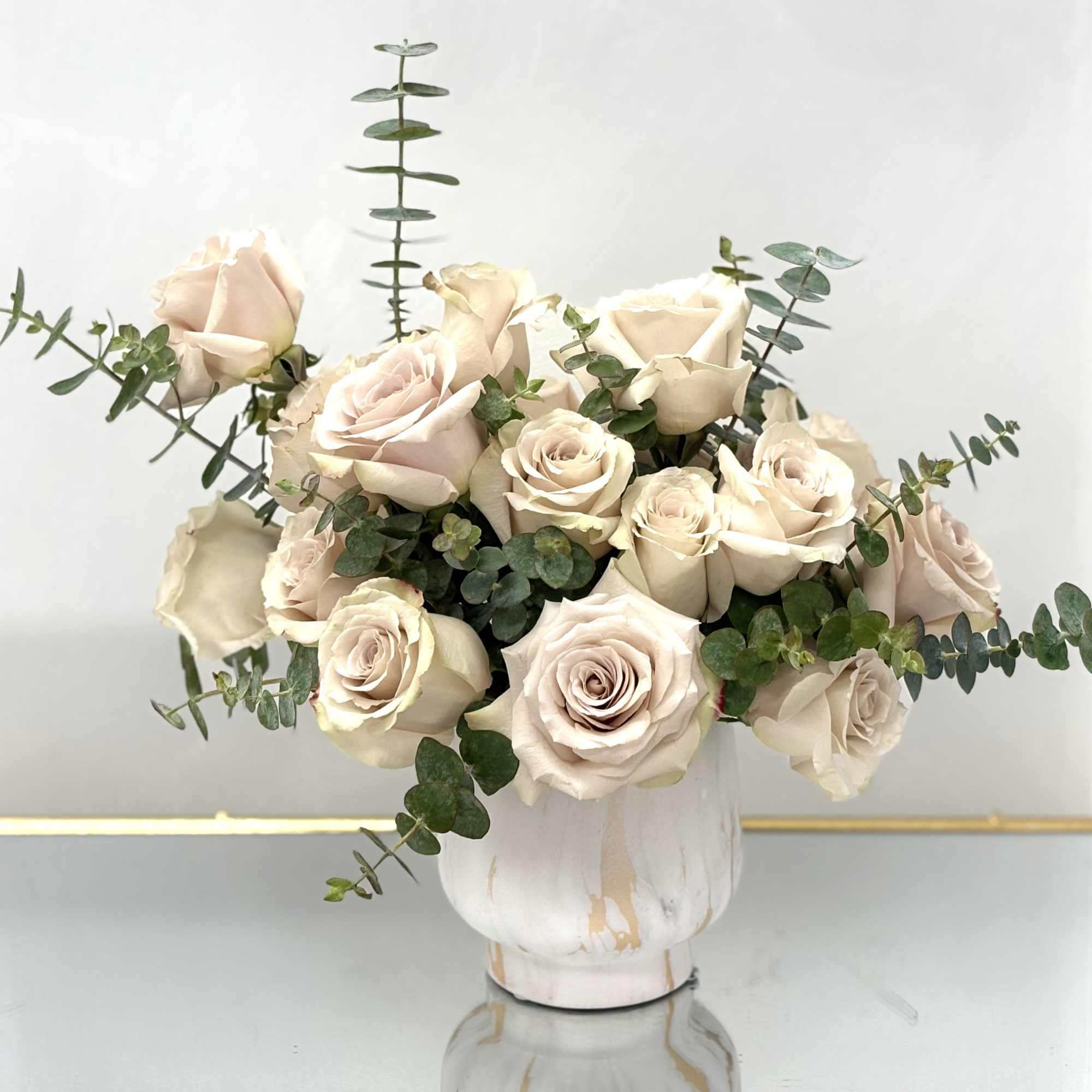 Cream rose bouquet in a white vase with eucalyptus