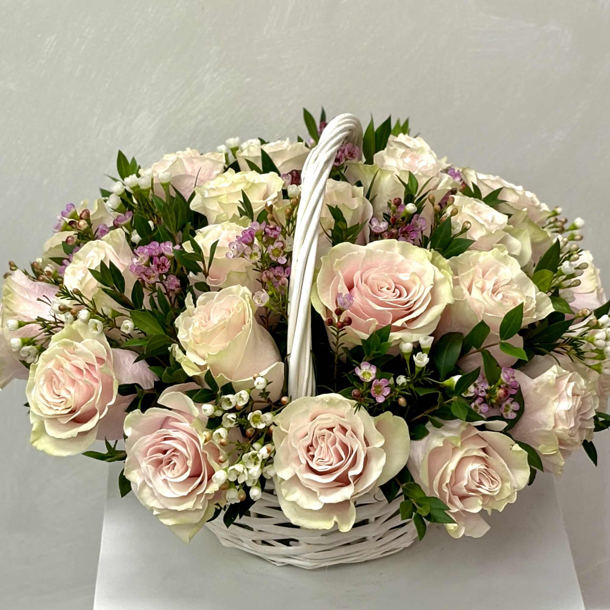 Basket of pale pink roses with small white and purple filler flowers