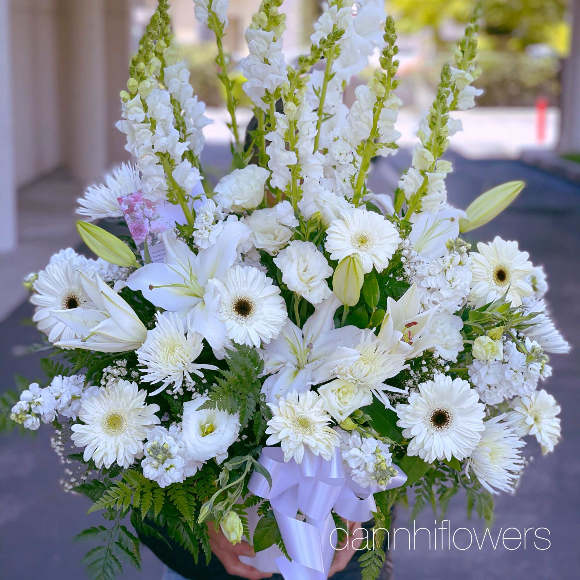 Large white bouquet with lilies, gerbera daisies, and snapdragons tied with a ribbon