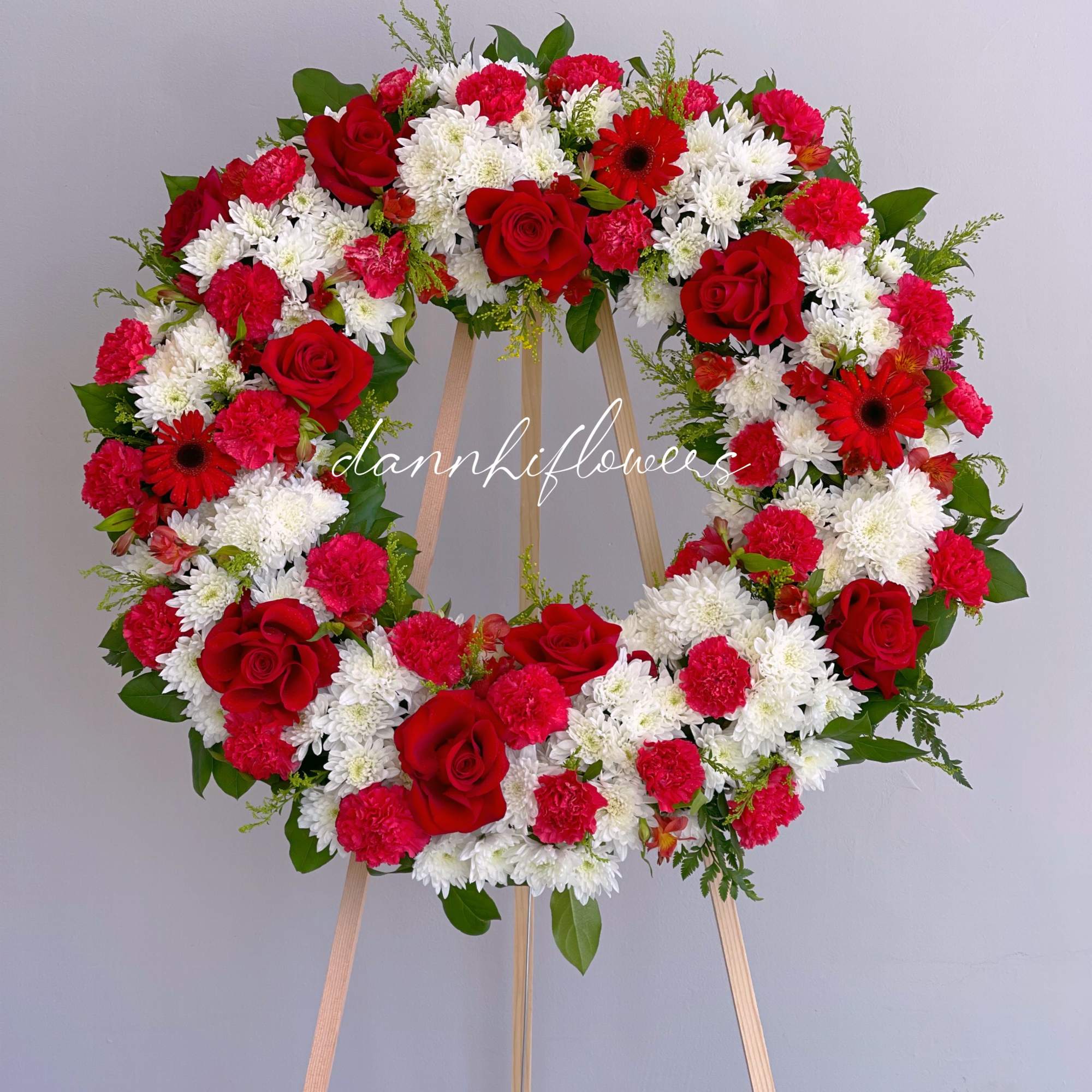 Red and white floral wreath on a wooden easel