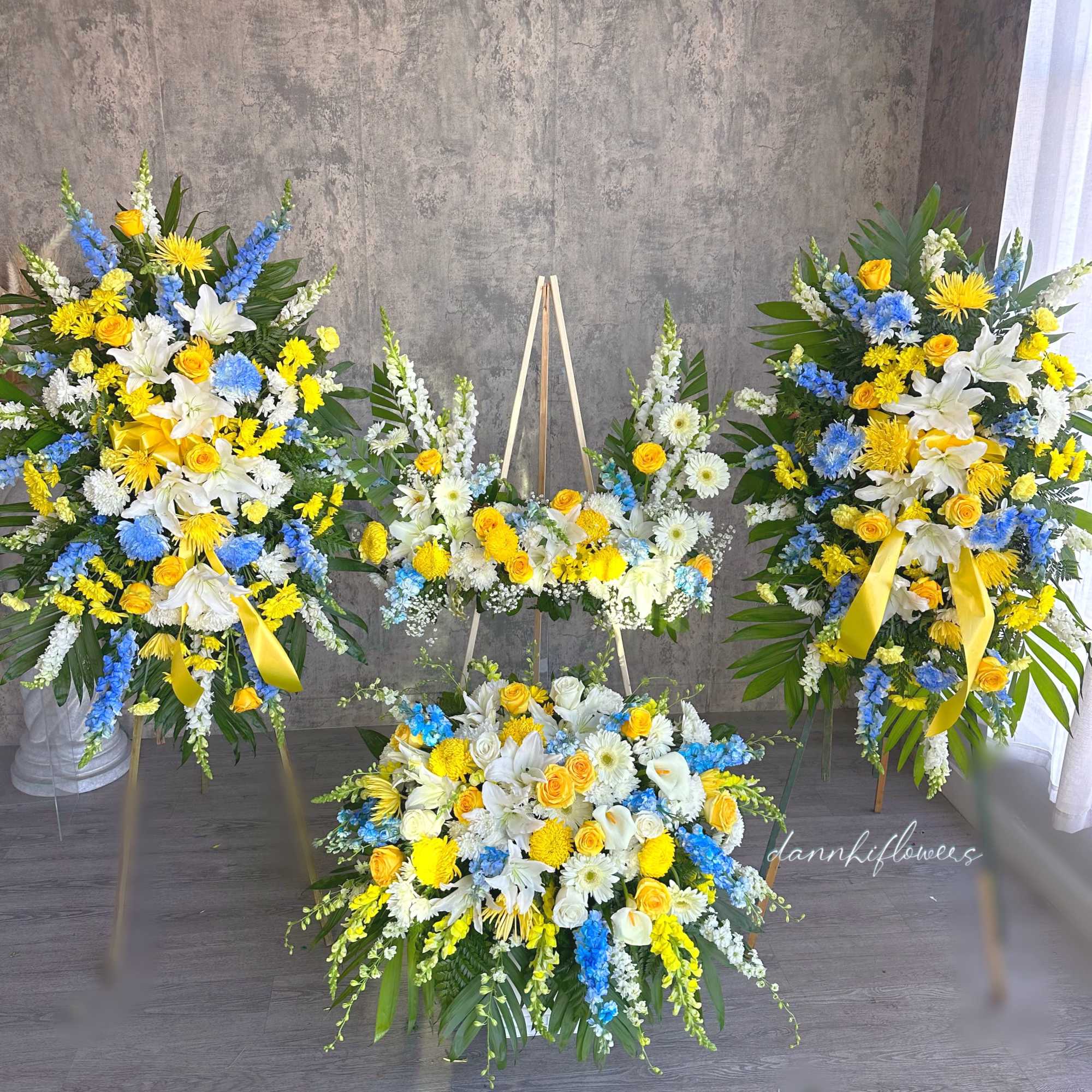 Three large floral standing sprays with yellow, white, and blue flowers