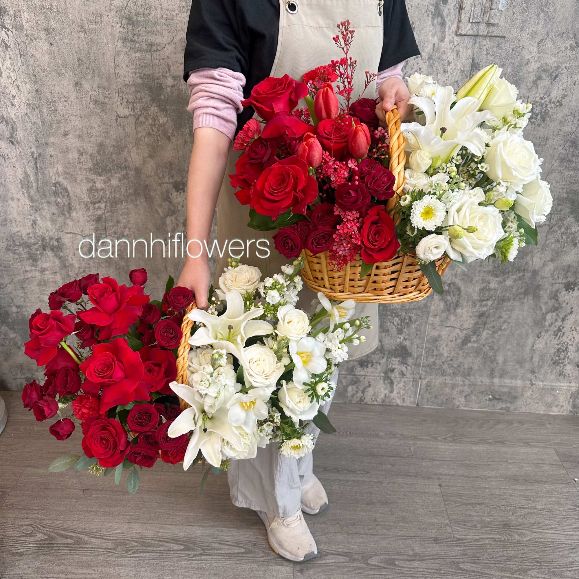Person holding large red and white flower baskets