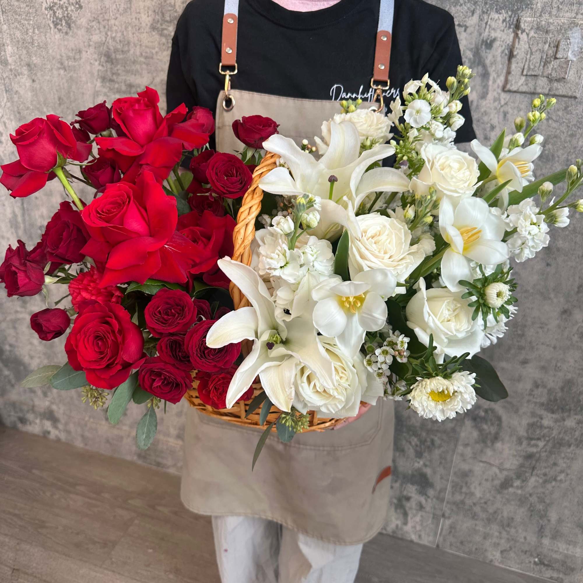 Basket arrangement of red and white roses with white lilies
